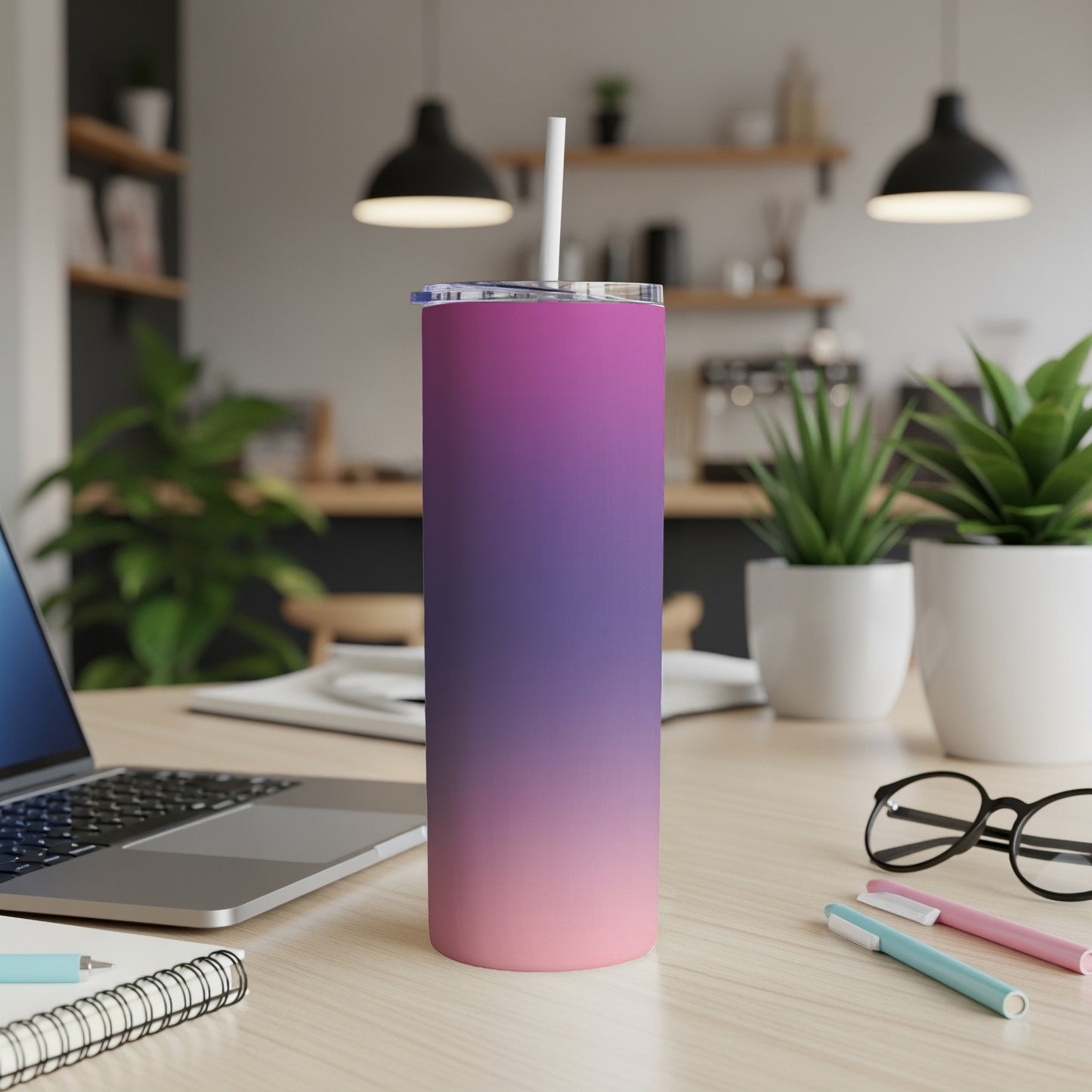 Gradient pink and purple tumbler with straw on desk.