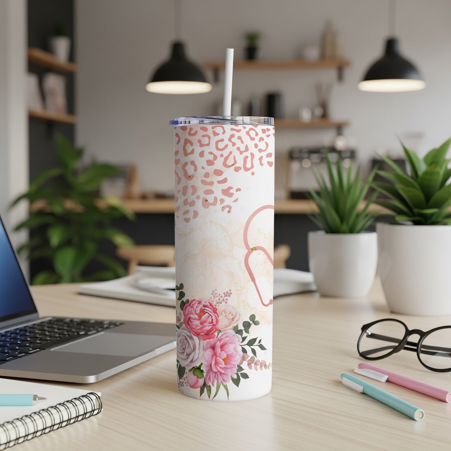 Leopard print and floral patterned insulated tumbler with straw on desk.