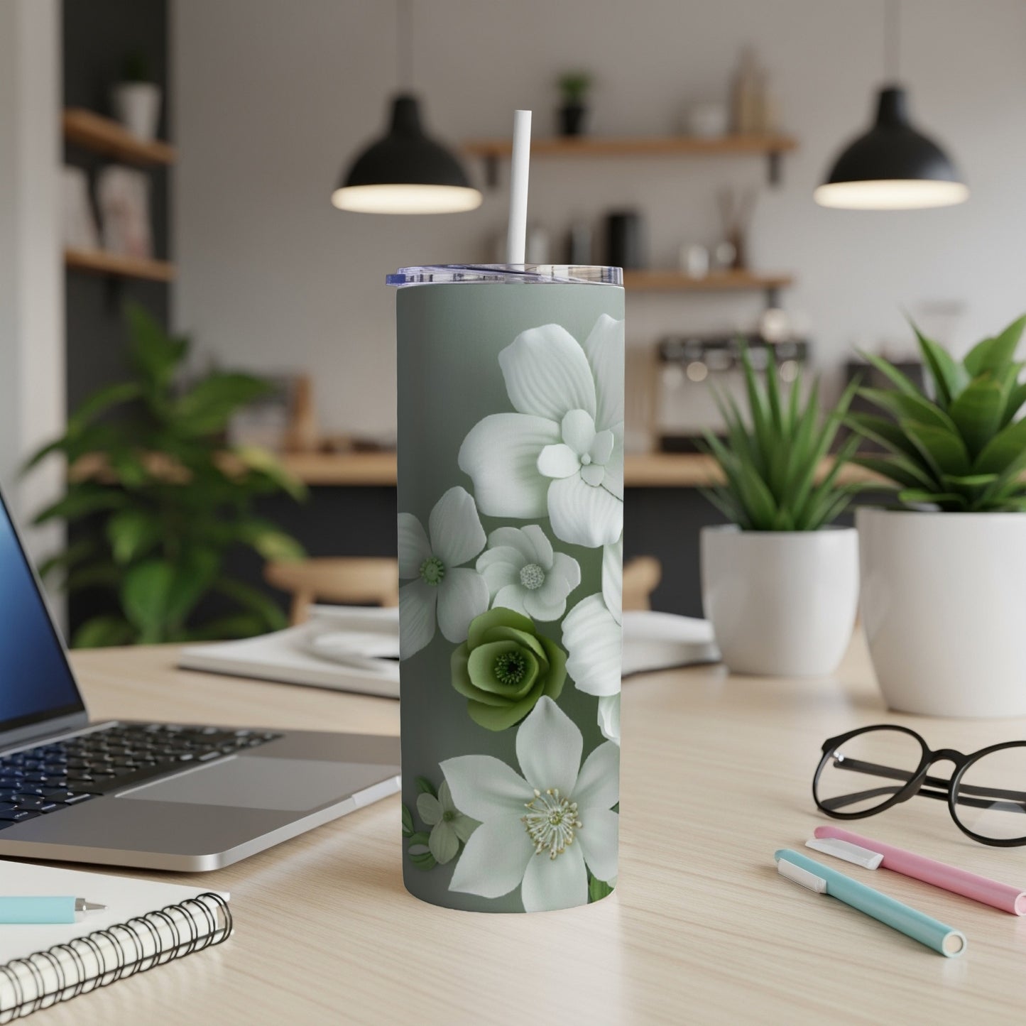 Green floral tumbler with a white straw on a desk.