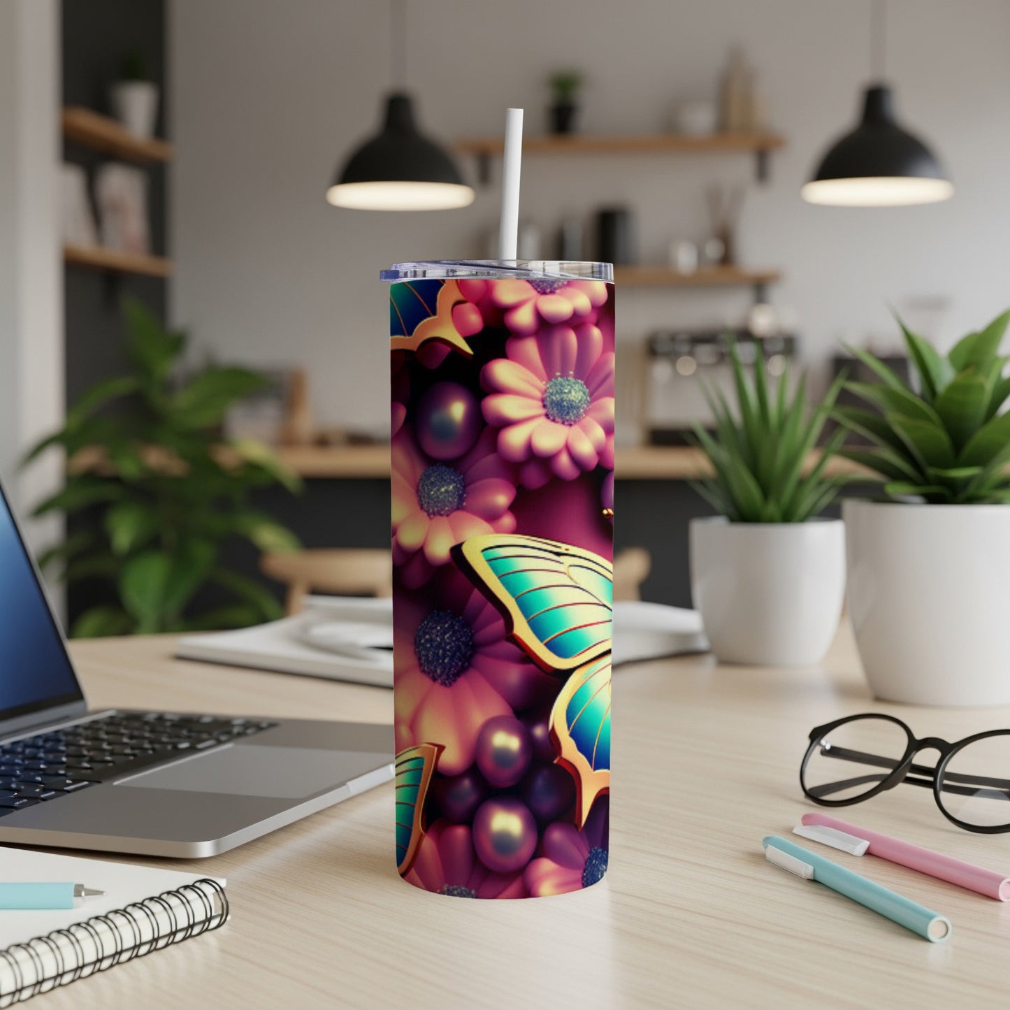 Tumbler with butterfly and floral pattern, straw in lid, on desk.