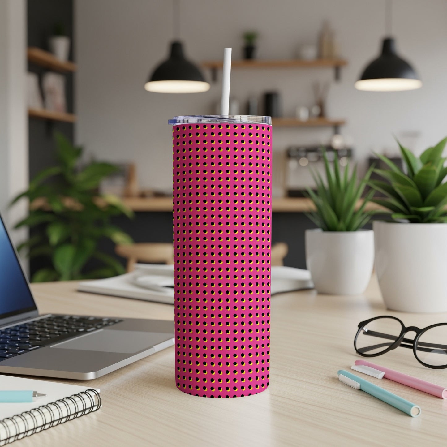 Pink tumbler with yellow and black polka dots, with a white straw.