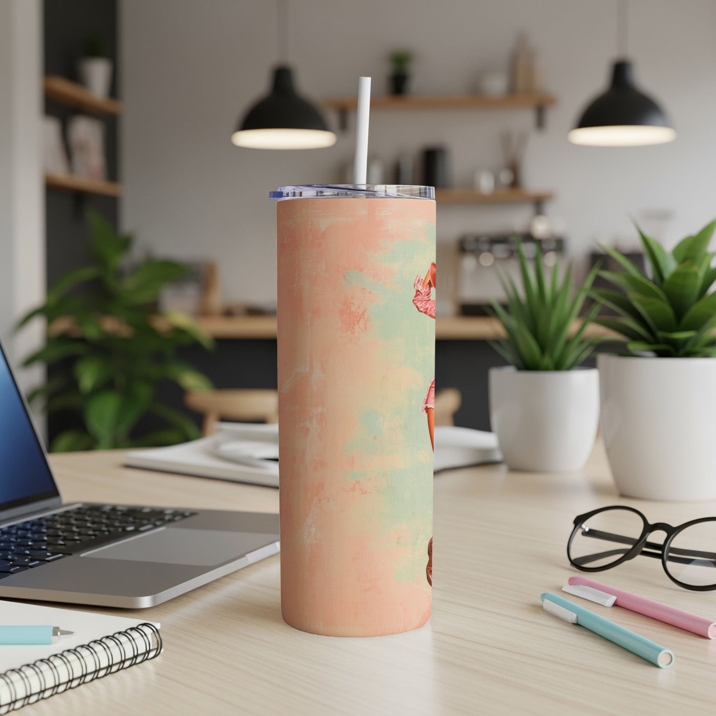 Peach tumbler with colorful mushroom designs on a desk.
