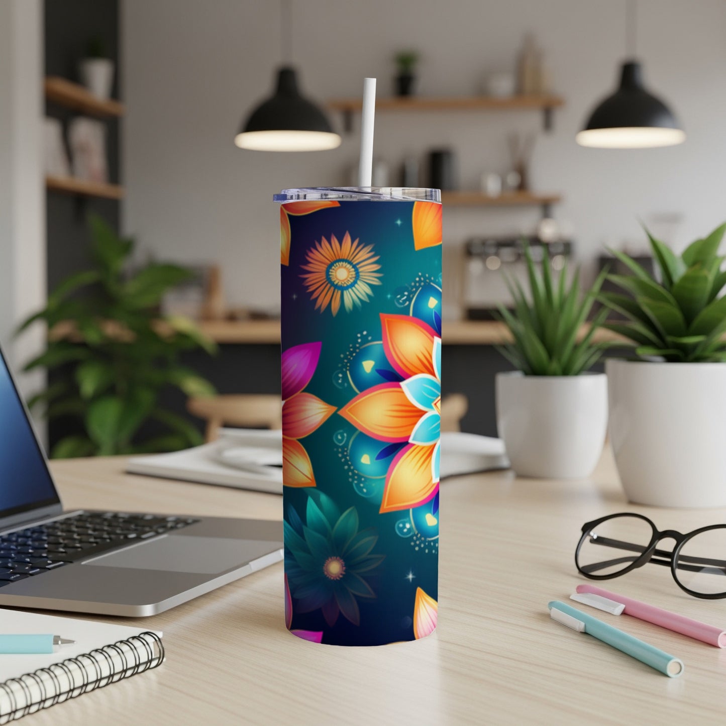 Tall tumbler with colorful floral pattern and straw, on a desk.