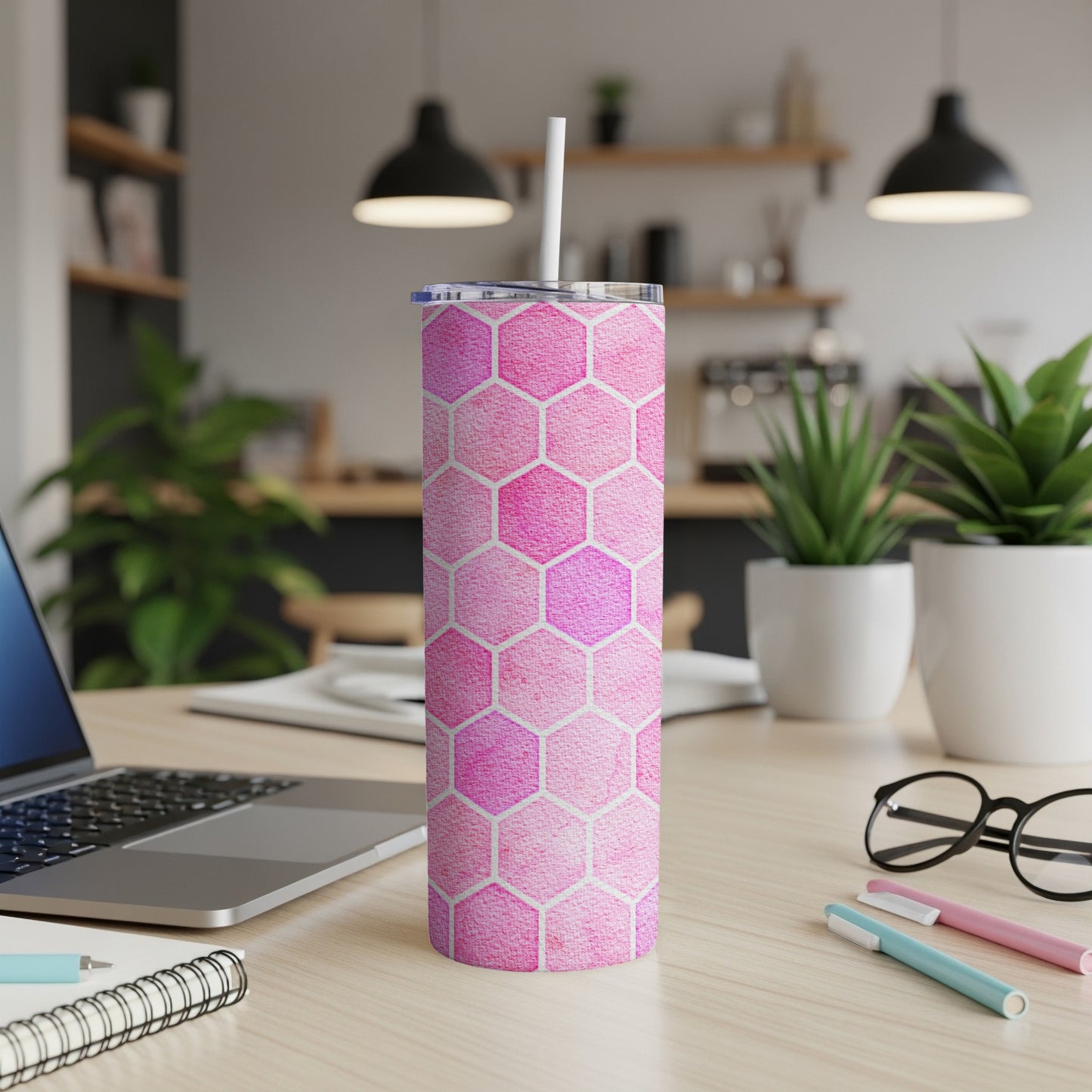 Pink hexagon pattern tumbler with white straw on a wooden desk.