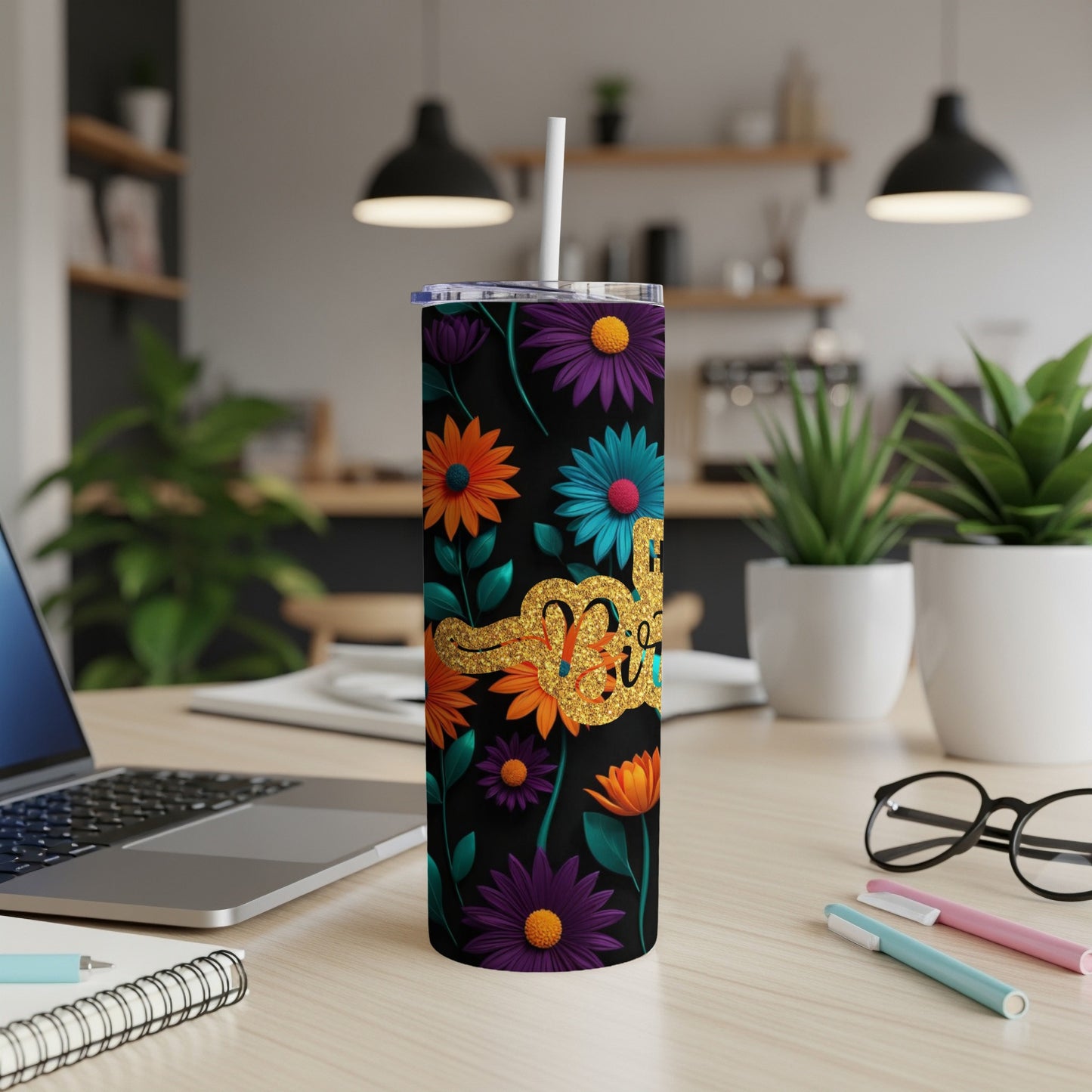 Black tumbler with colorful flowers and glitter accents, straw inserted.