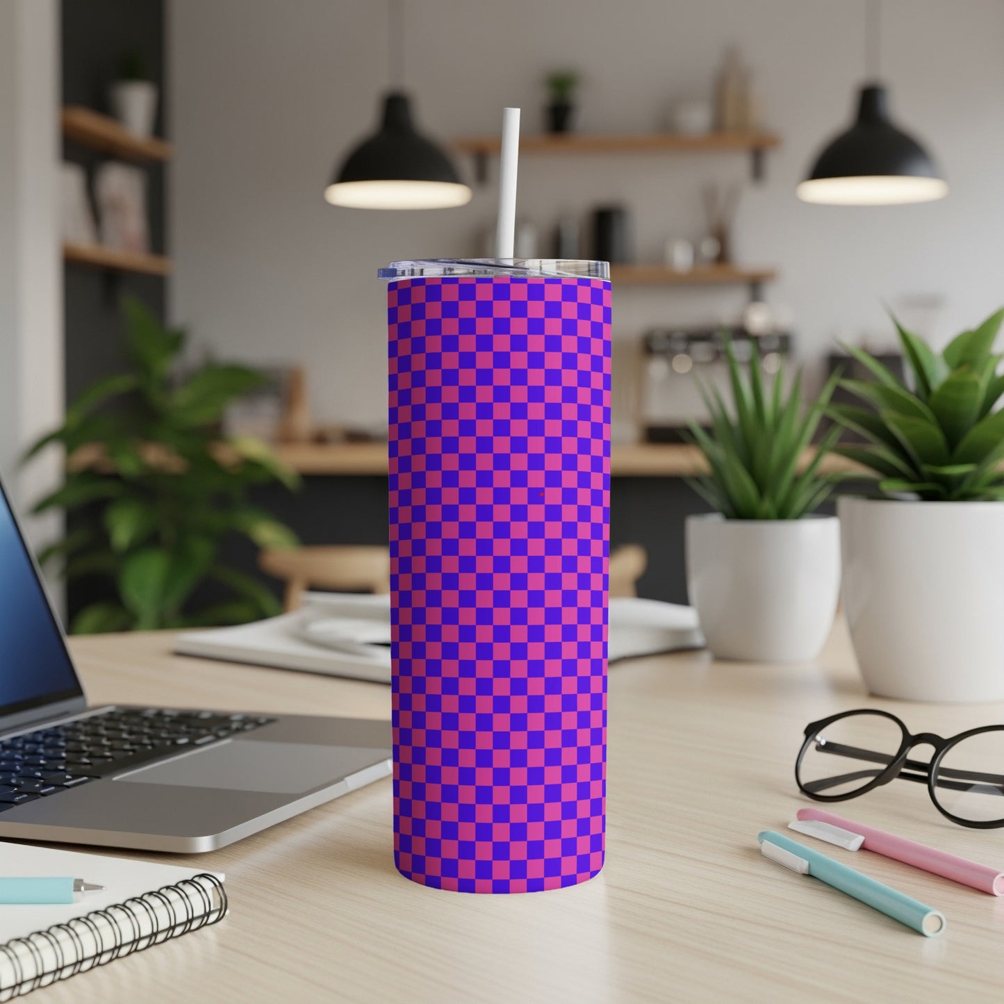 Blue and purple checkered tumbler with a straw on a desk.