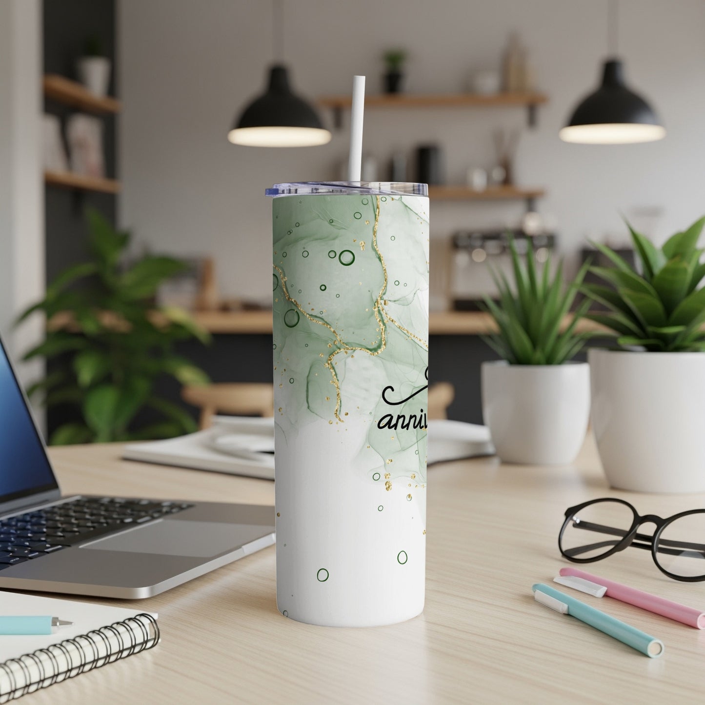 Green marbled tumbler with "anniversary" text, on a desk.