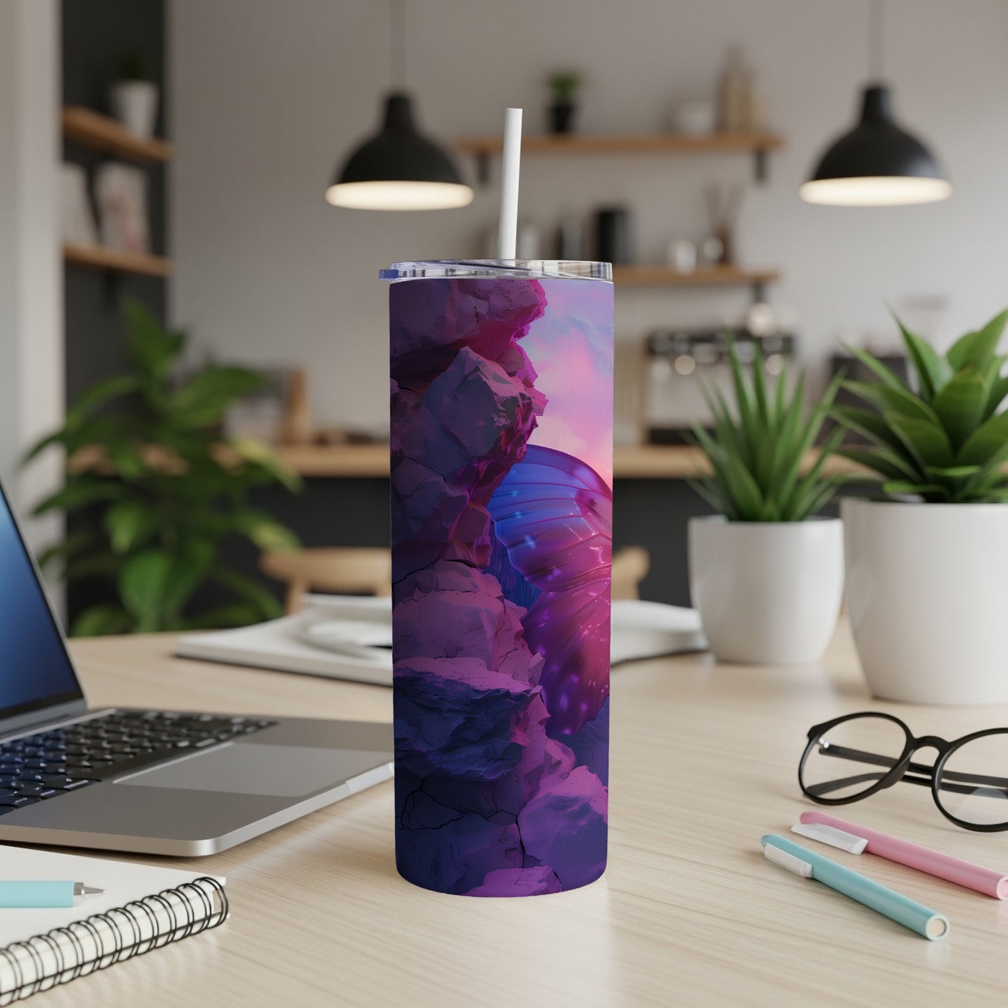 Tumbler with butterfly wing design on desk next to laptop and pens.