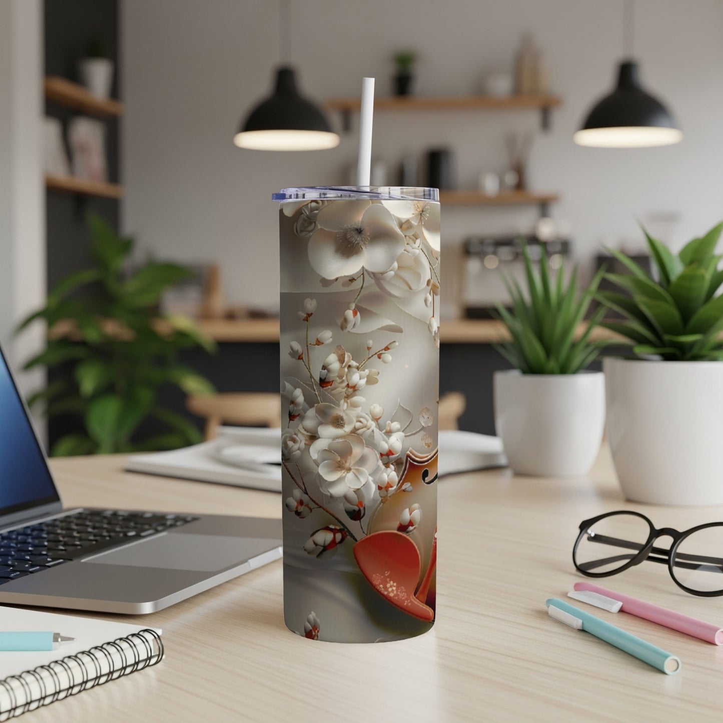 Floral design tumbler with straw on a desk.