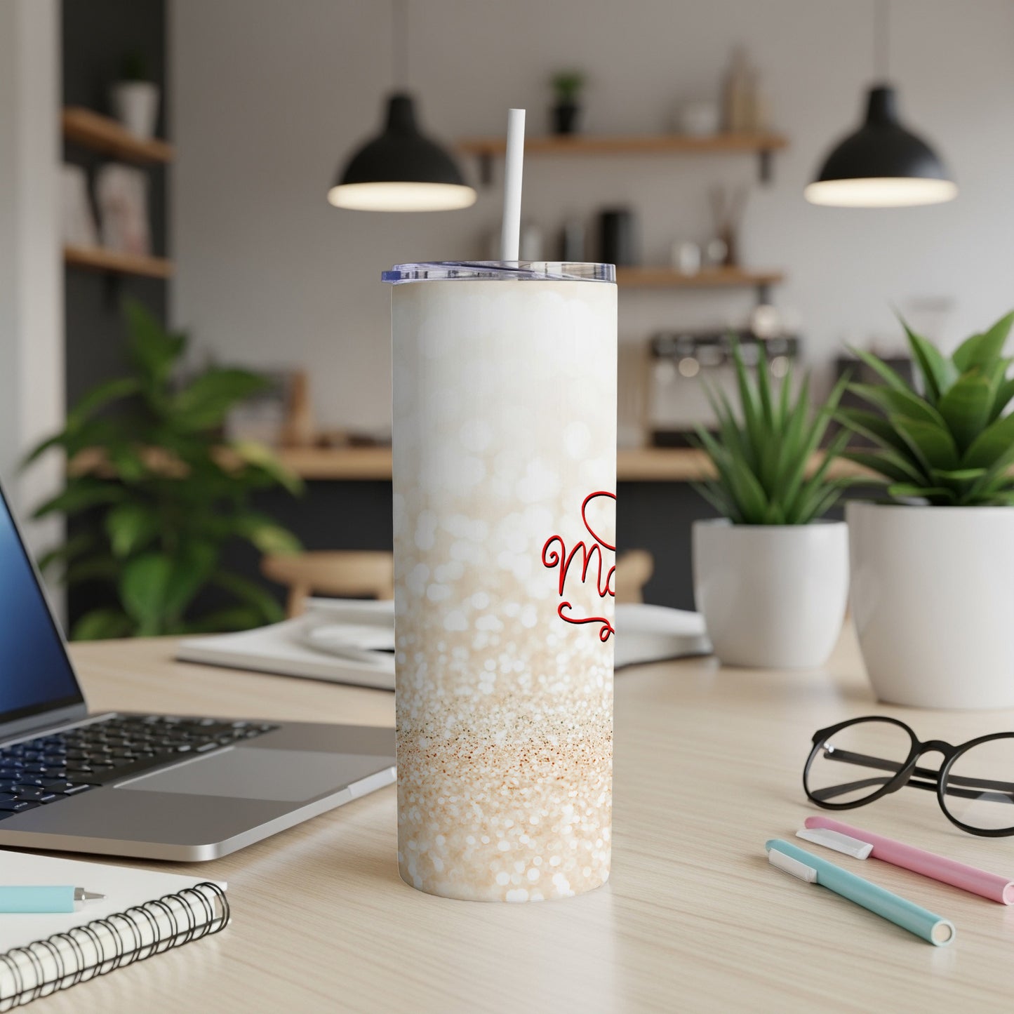 White speckled tumbler with "Merry" text and a straw on a desk.