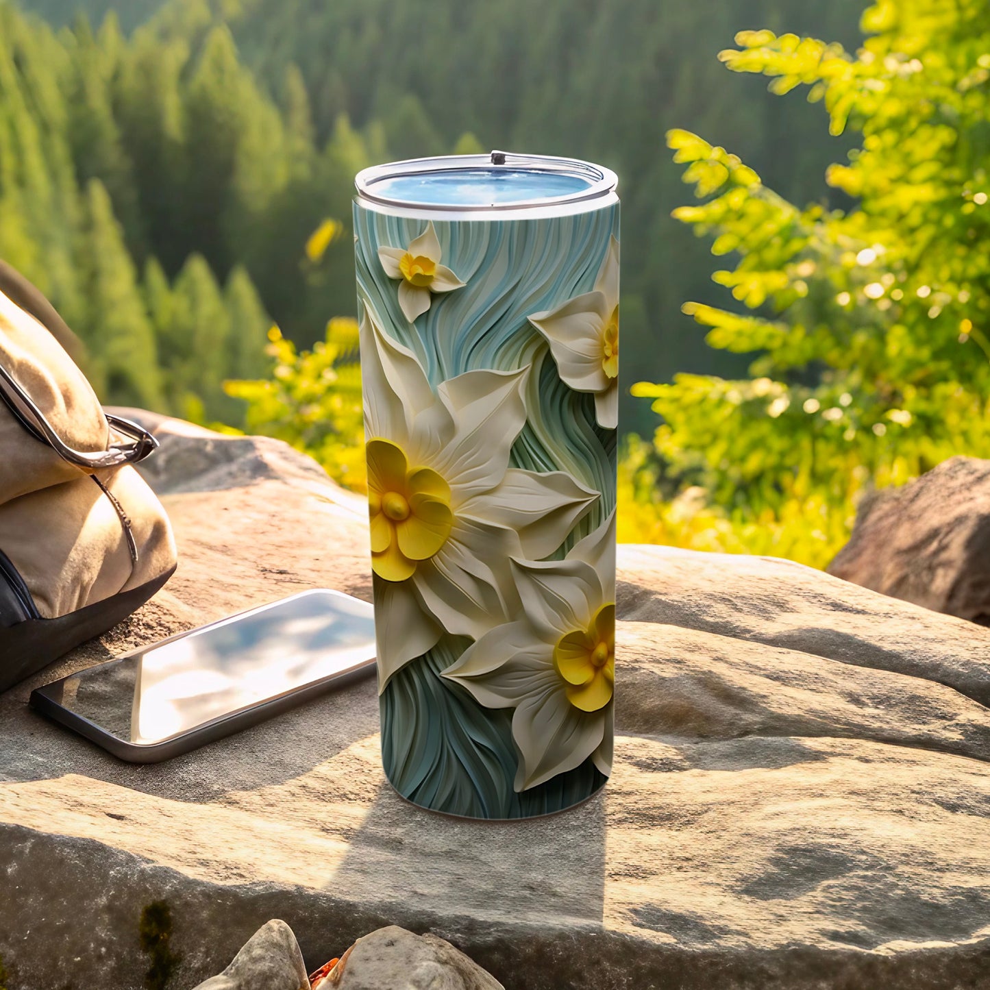 3D floral design on a blue tumbler next to a phone and bag.