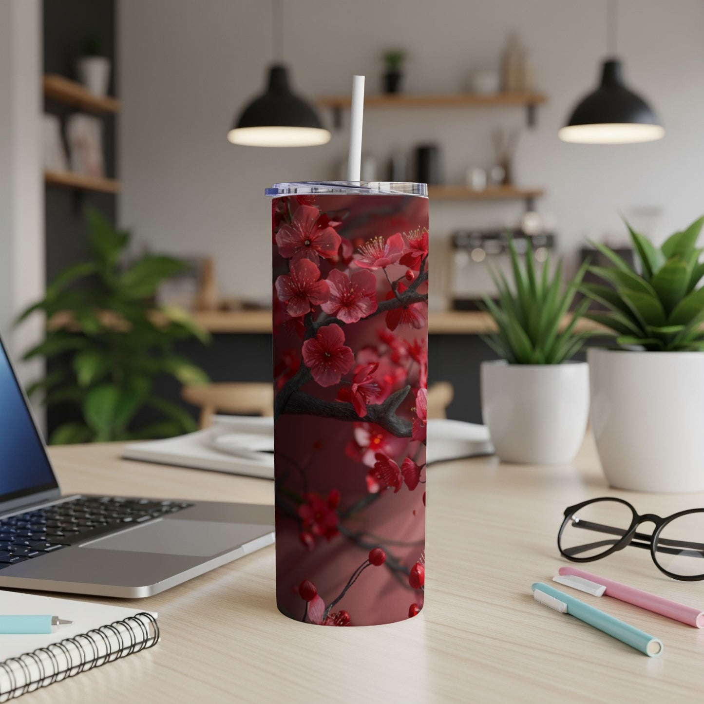 Red cherry blossoms on a dark branch decorate a tall, insulated tumbler with a straw.
