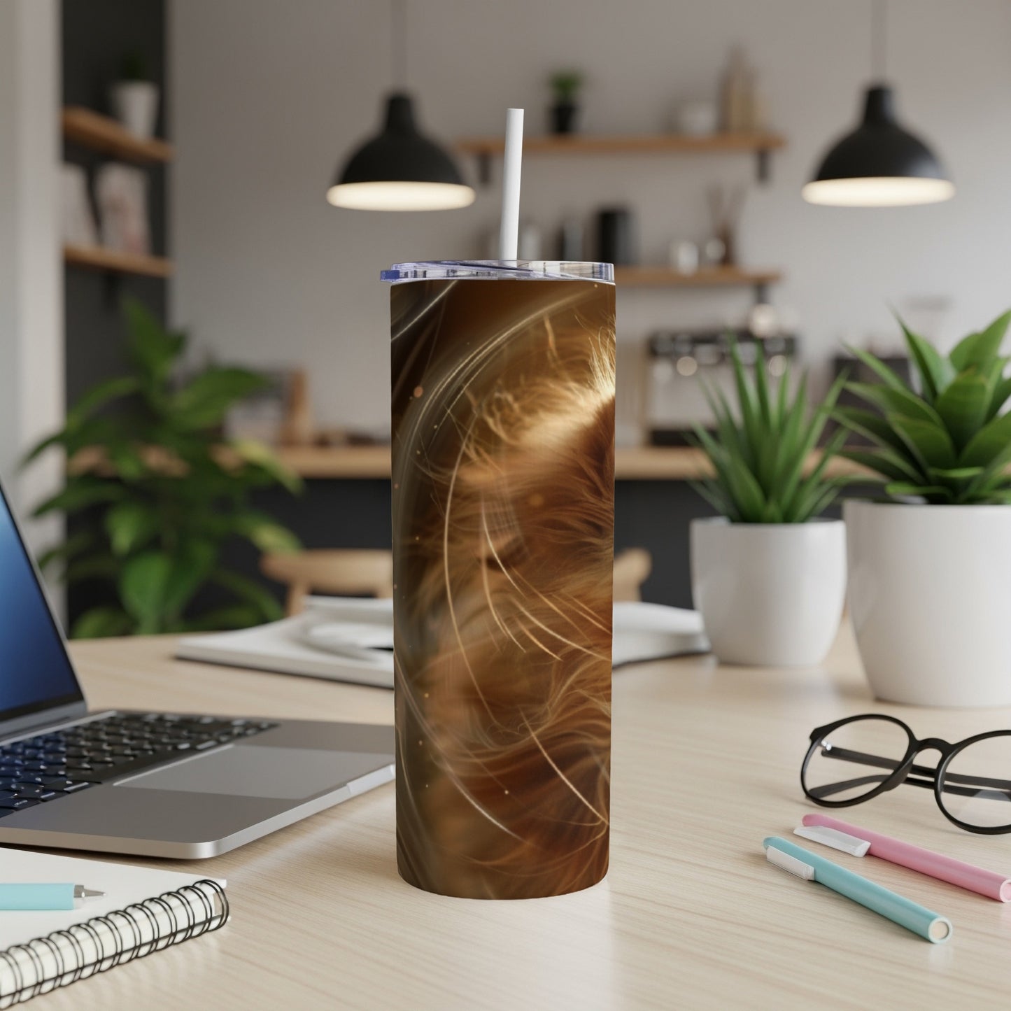 Brown speckled tumbler with straw on a desk with a laptop and pens.