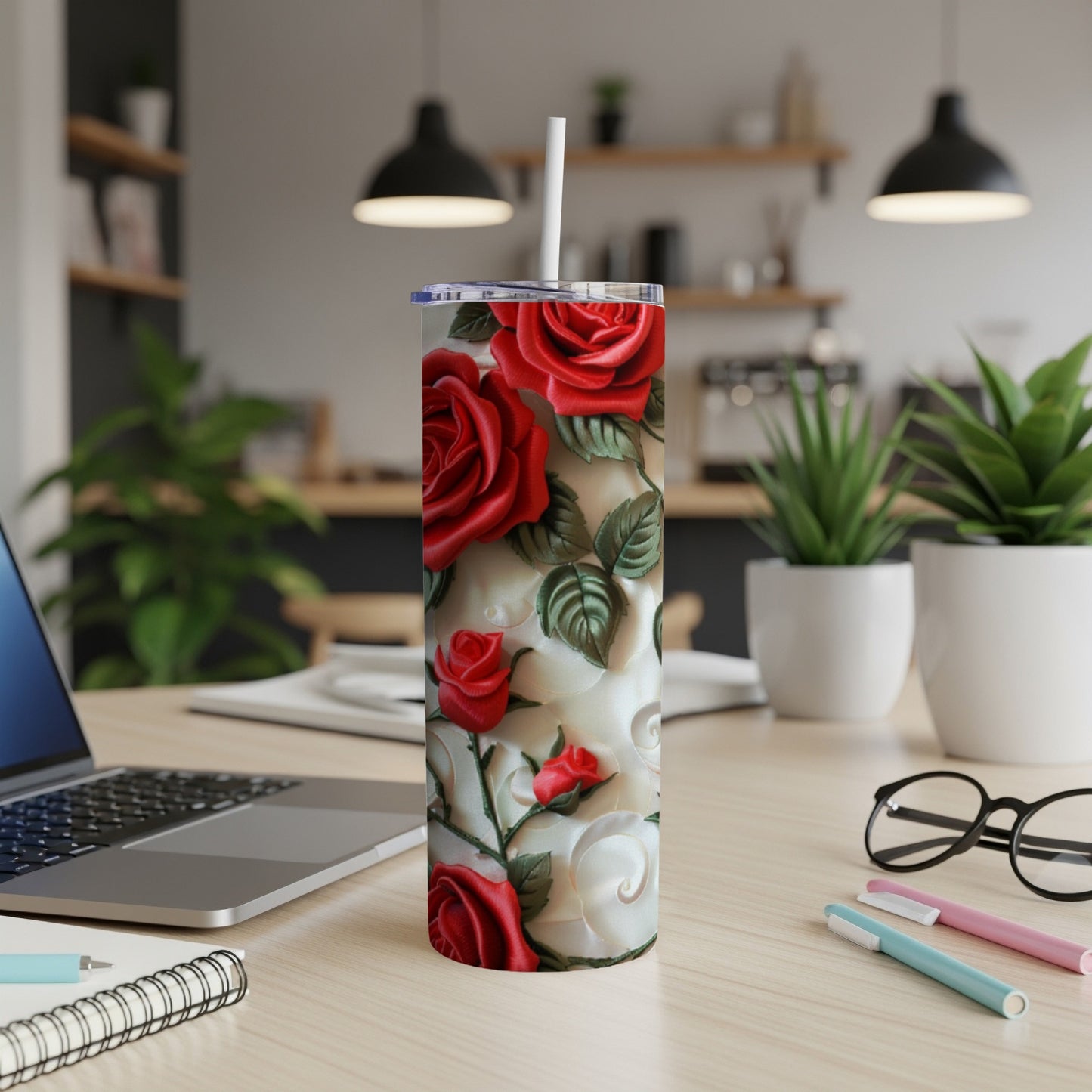 Tall tumbler with embossed red and white roses, a straw, and office desk background.