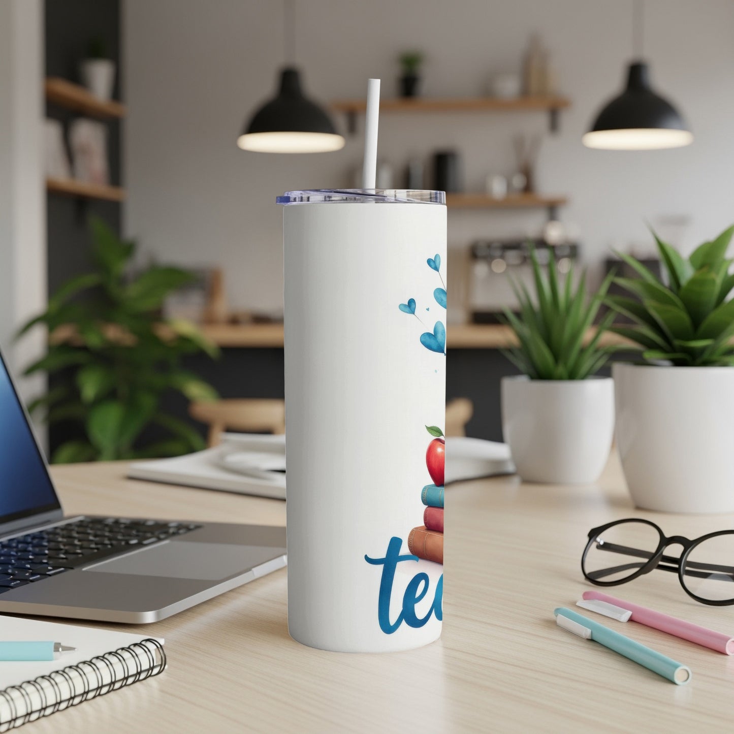 White tumbler with "teacher" text and stack of colorful books.