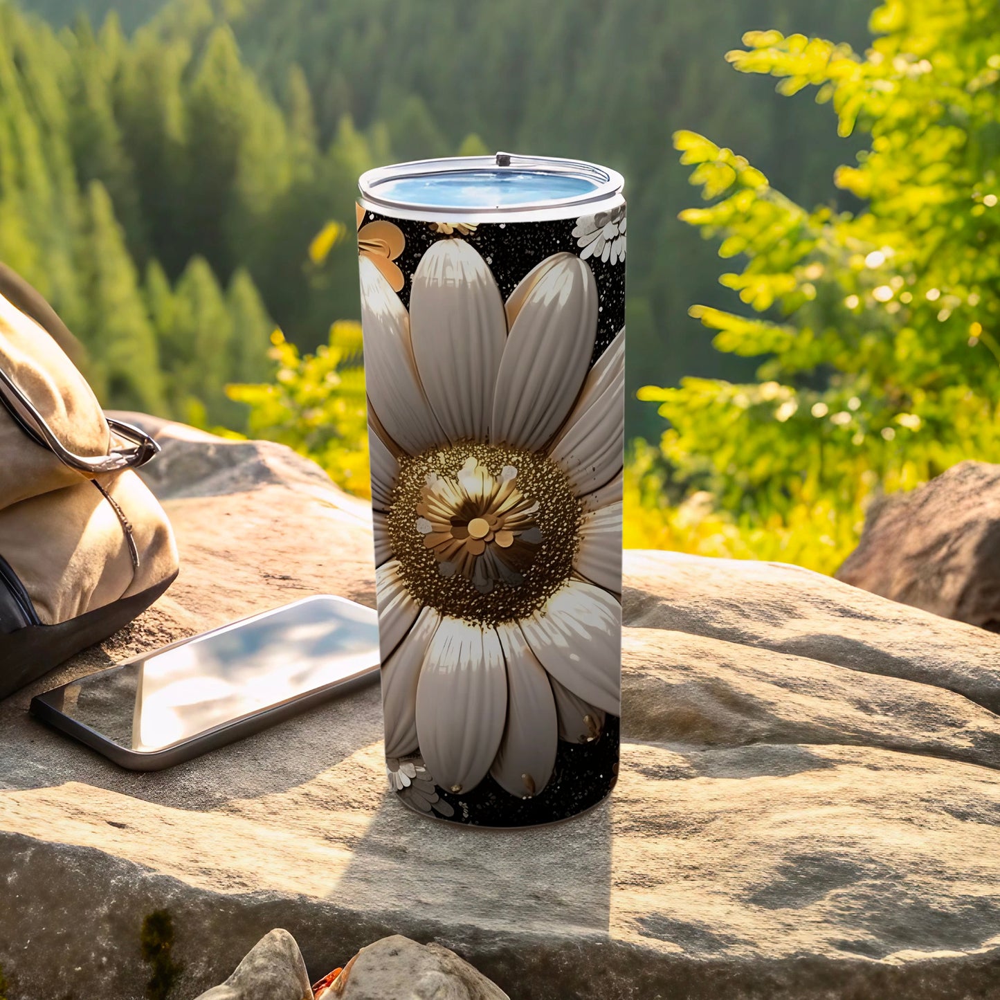 White daisy tumbler with gold accents on a rocky surface next to a phone.