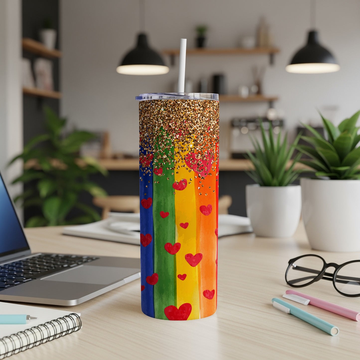 Rainbow tumbler with glitter top and red hearts, next to a laptop.