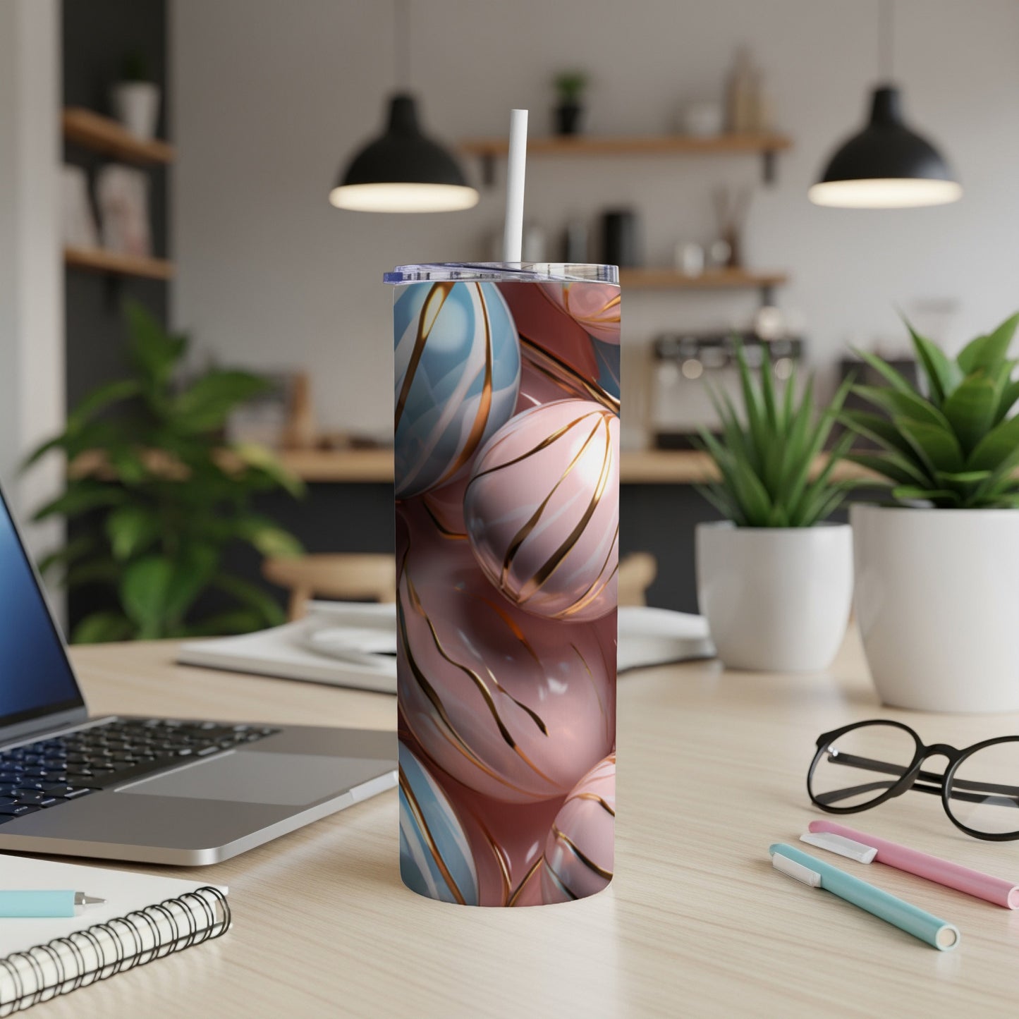 Pink and blue marbled tumbler with gold stripe details on a desk.