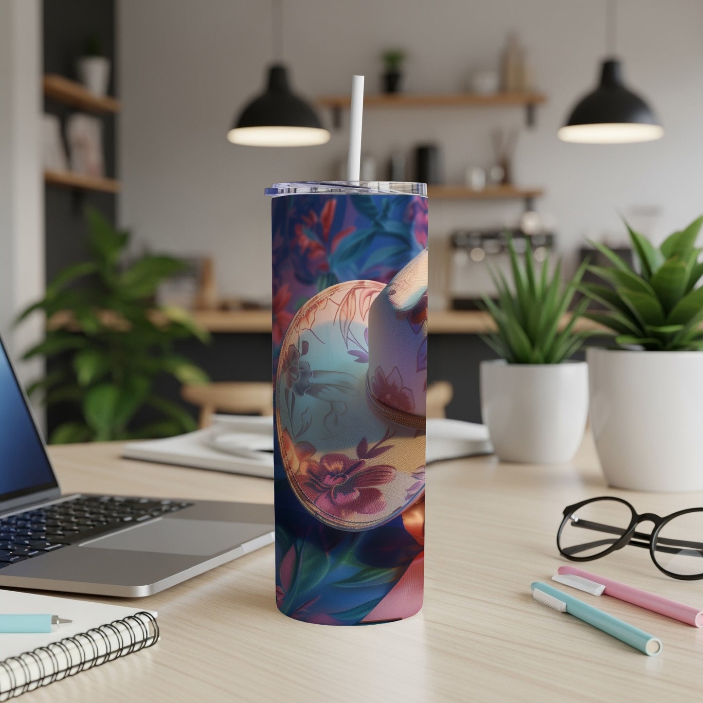 Tumbler with floral and geometric pattern, straw, laptop, and notebooks.