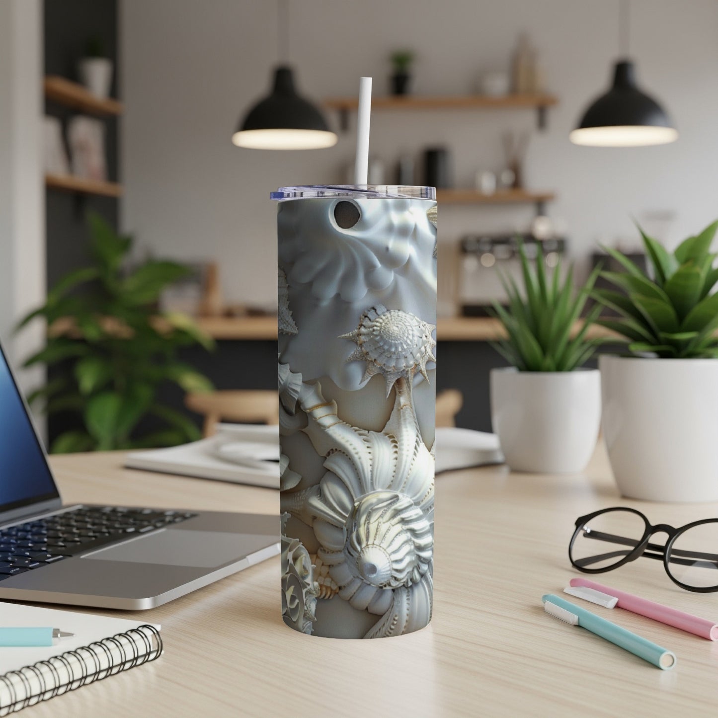 Seashell pattern tumbler with straw on a wooden desk.