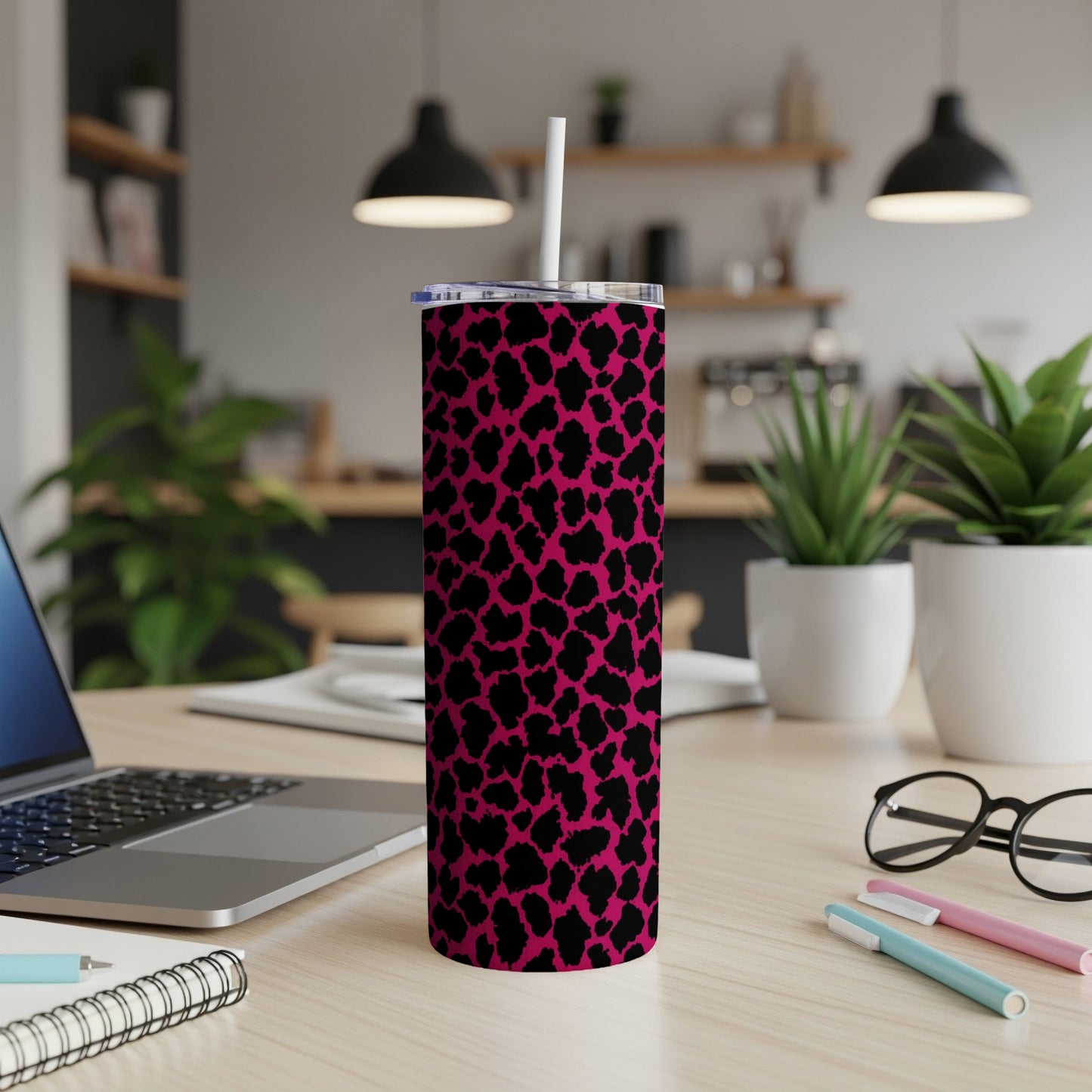 Pink tumbler with black leopard print and straw on a desk.