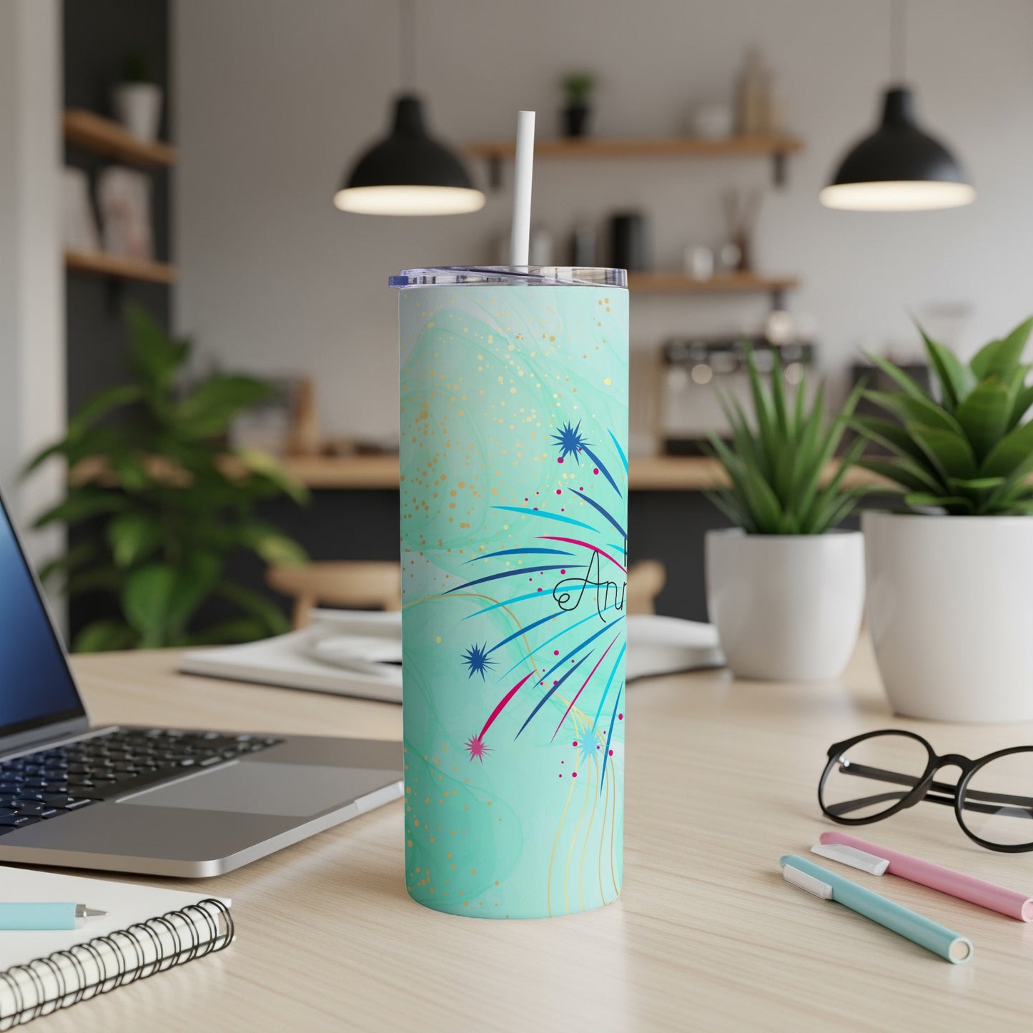 Turquoise tumbler with fireworks design and a straw.