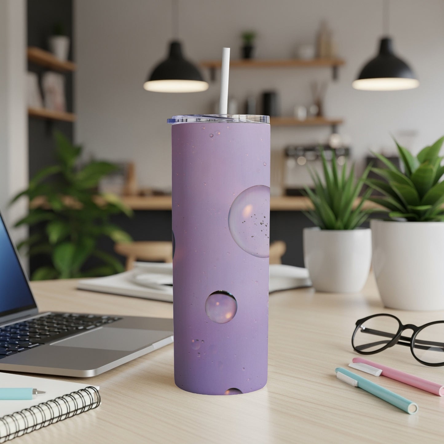 Purple tumbler with bubbly design on a desk next to a laptop.