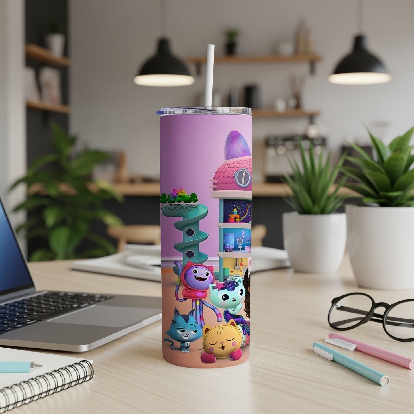 Gabby's Dollhouse characters on a pink tumbler with a straw, on a desk.