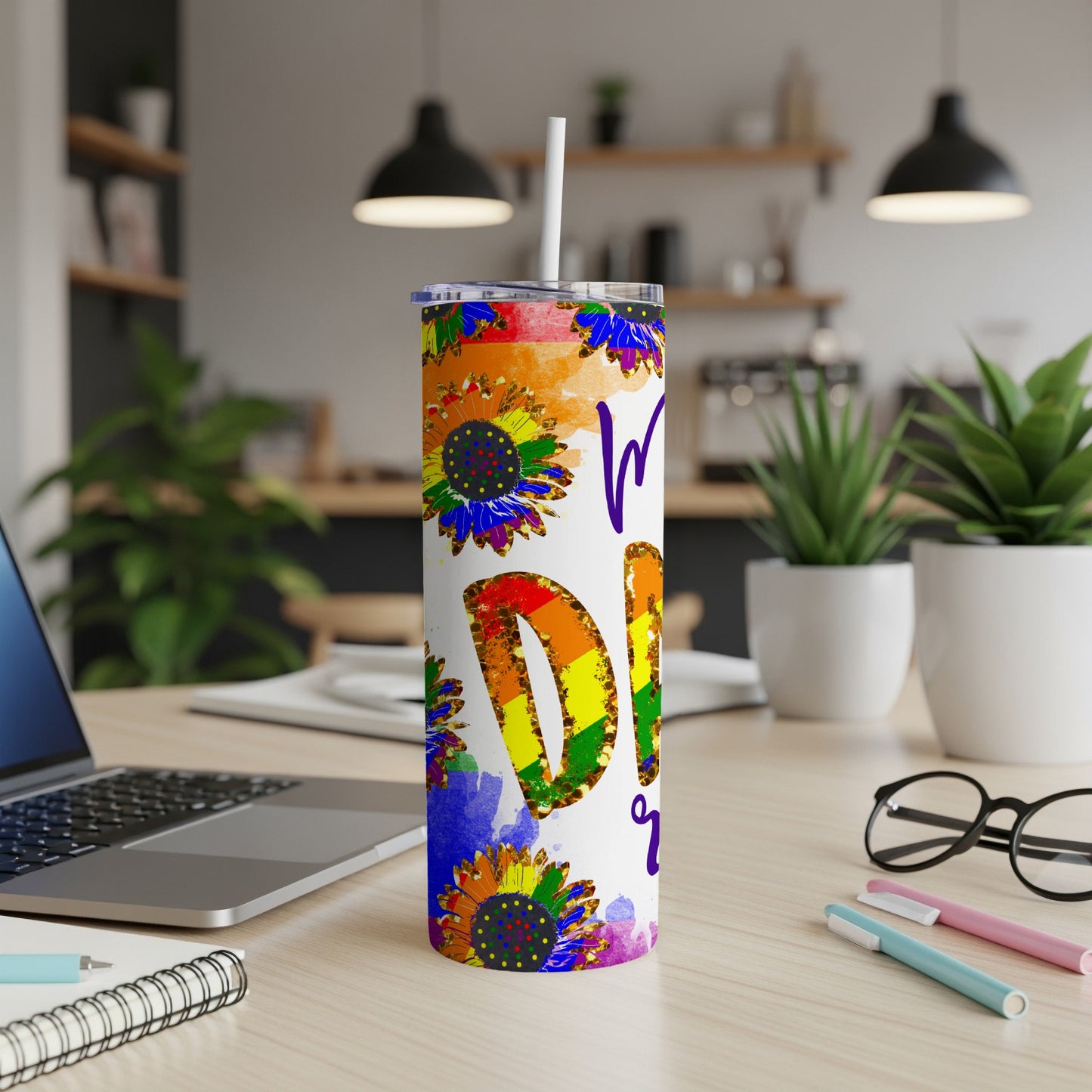 Rainbow sunflower tumbler with "Pride" text on a desk.