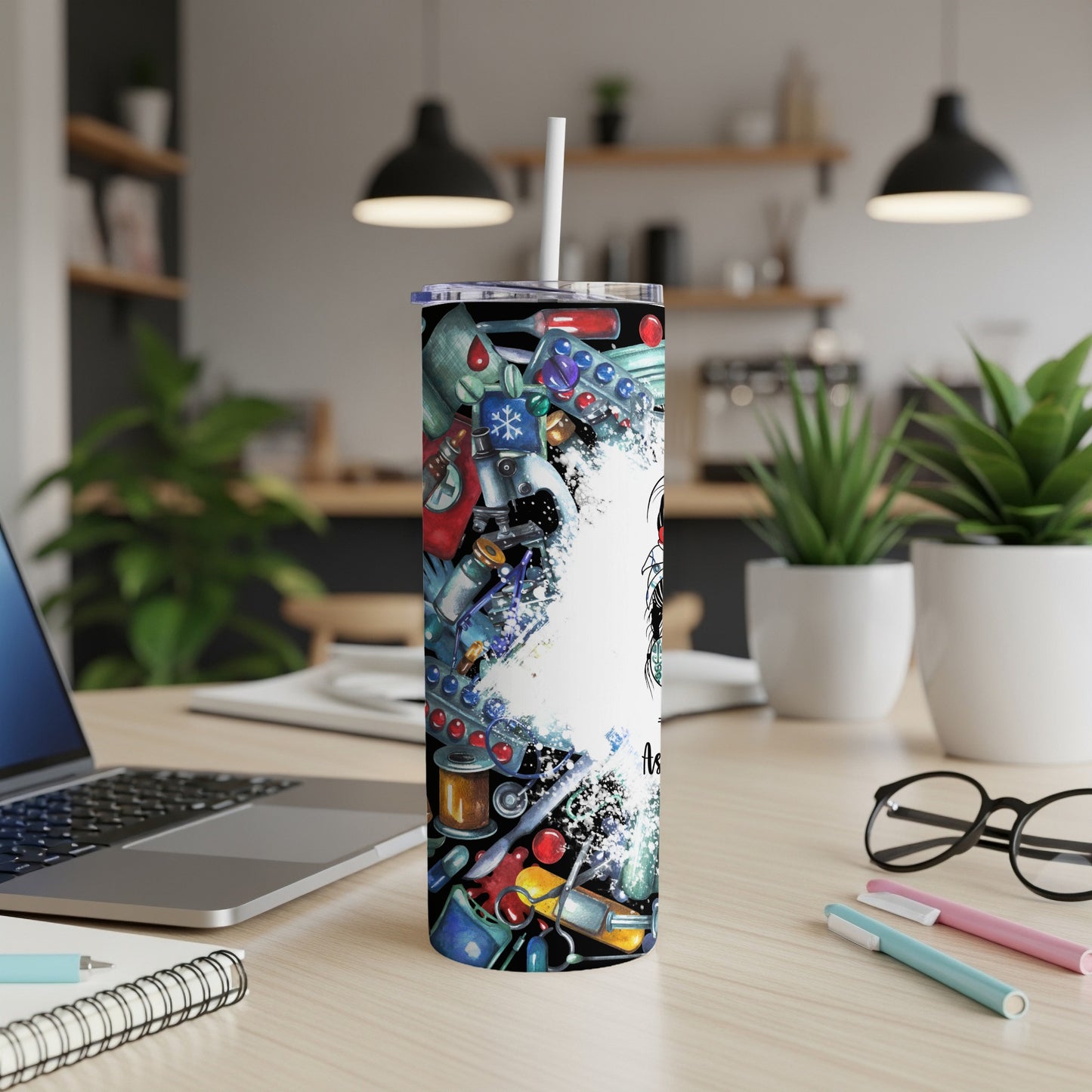 Tall tumbler with medical illustrations and white straw on a desk.