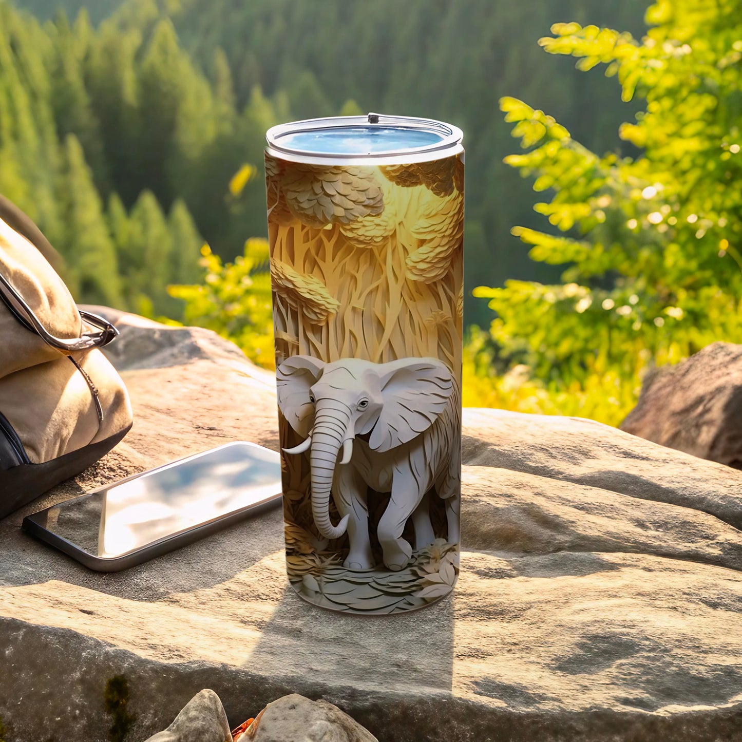 White elephant design on a tall tumbler, displayed outdoors with phone and backpack.