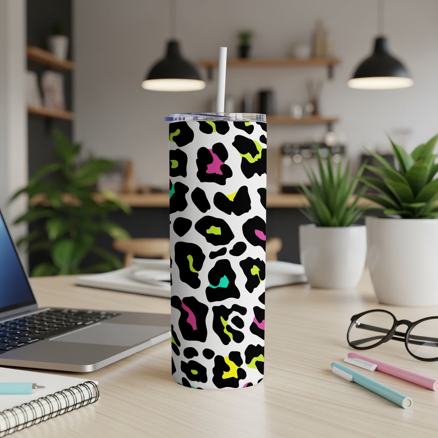 Tall tumbler with white background and colorful leopard print, featuring a straw.