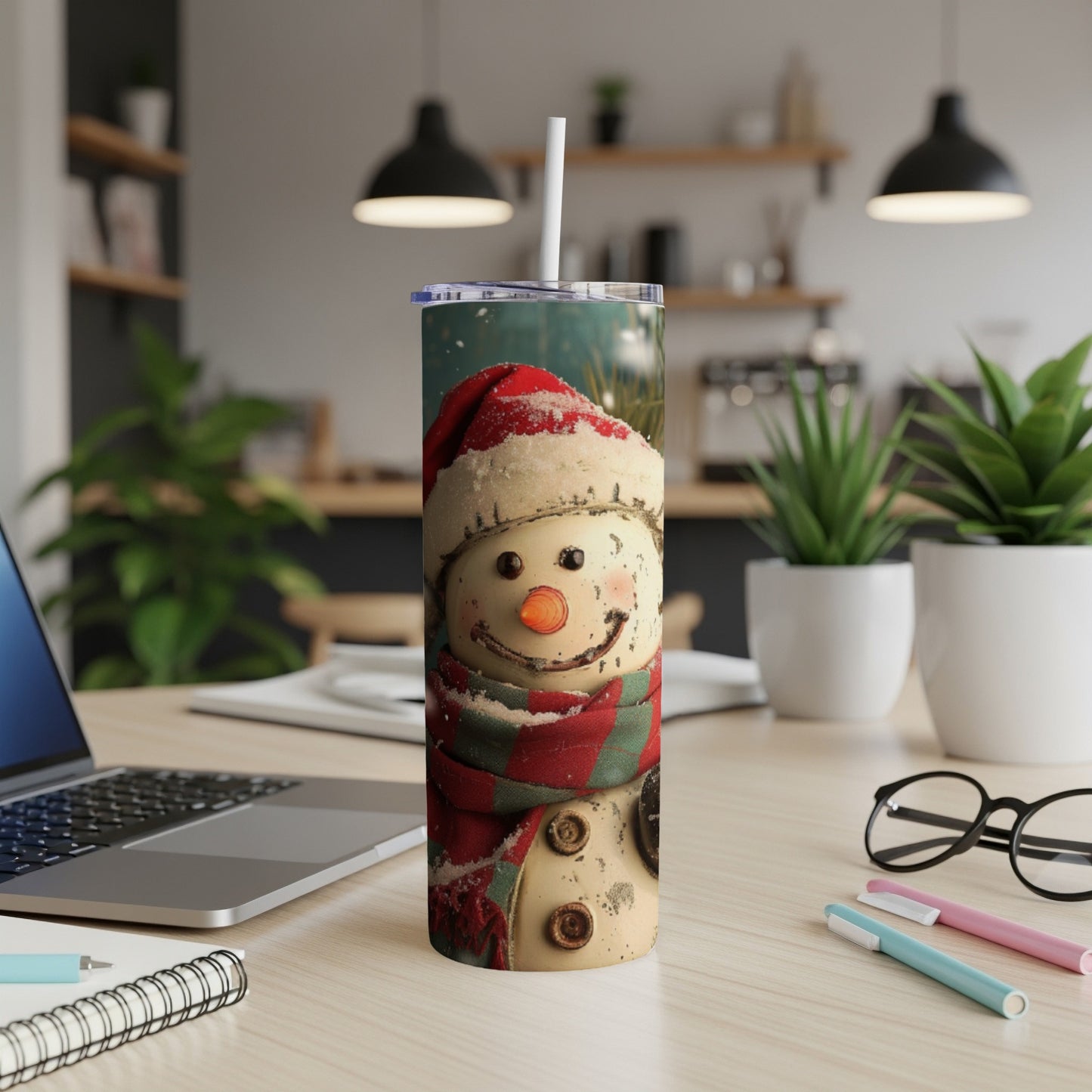Snowman tumbler with Santa hat and scarf on a desk.