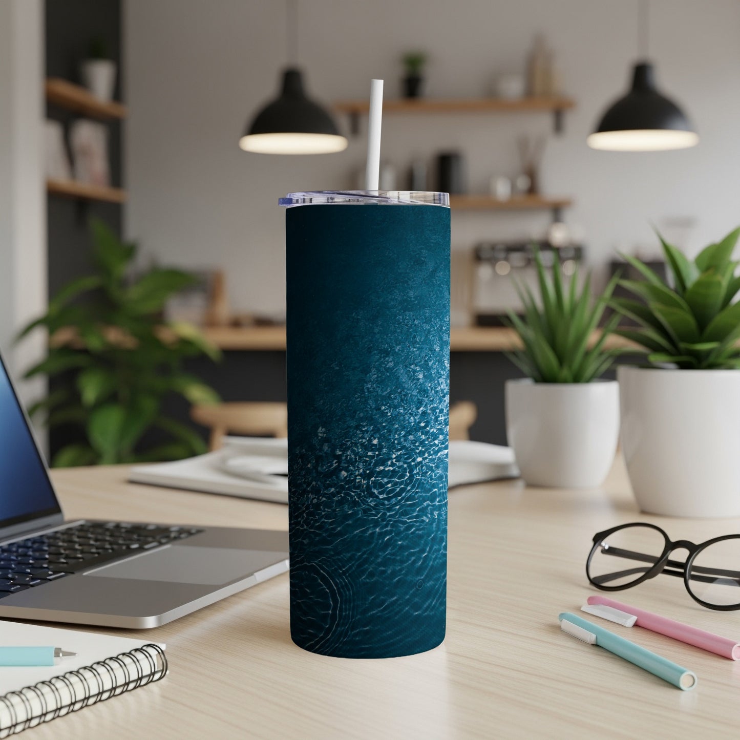 Blue tumbler with water ripple design and white straw on desk.