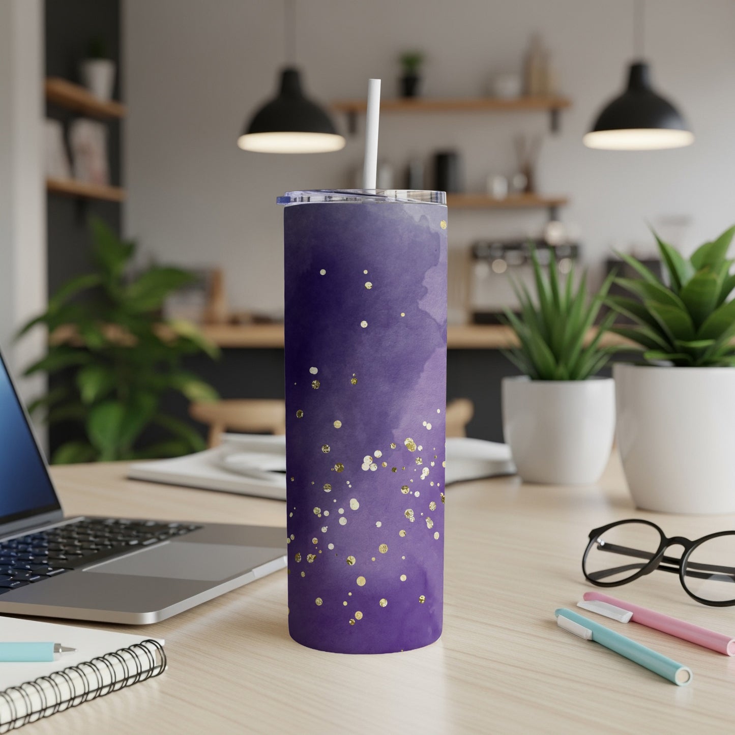 Purple tumbler with gold glitter and white lid on a desk.