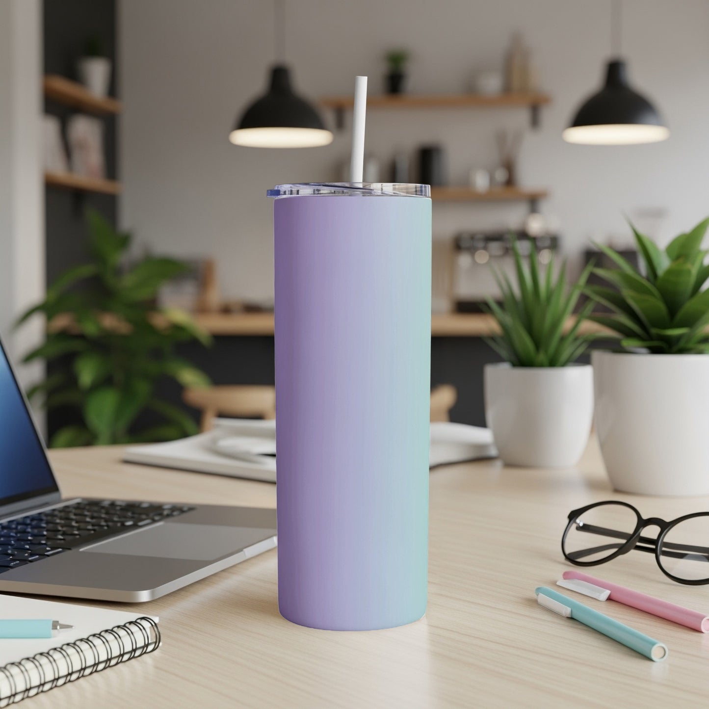 Gradient purple and teal tumbler with straw on a desk.