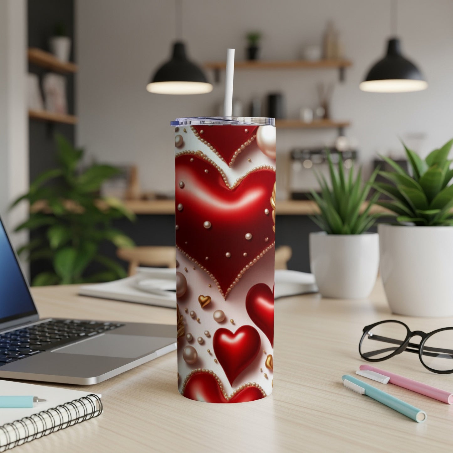 Red and gold heart pattern tumbler with straw on a desk.