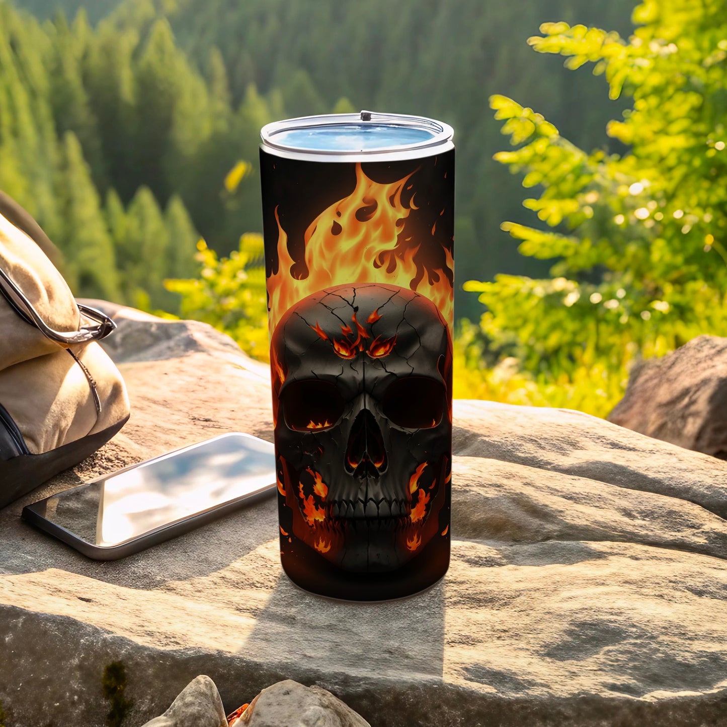 Black tumbler with flaming skull design on outdoor surface.