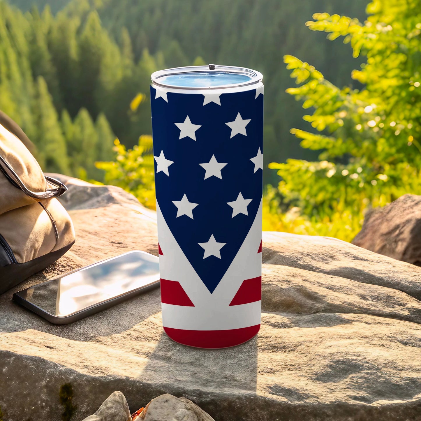 American flag tumbler on a rock with a backpack and phone.