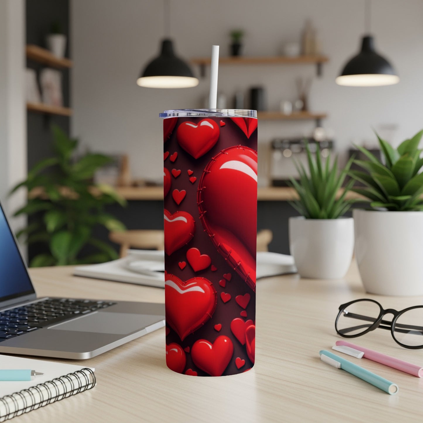 Red heart pattern on a tall tumbler with a straw on a desk.