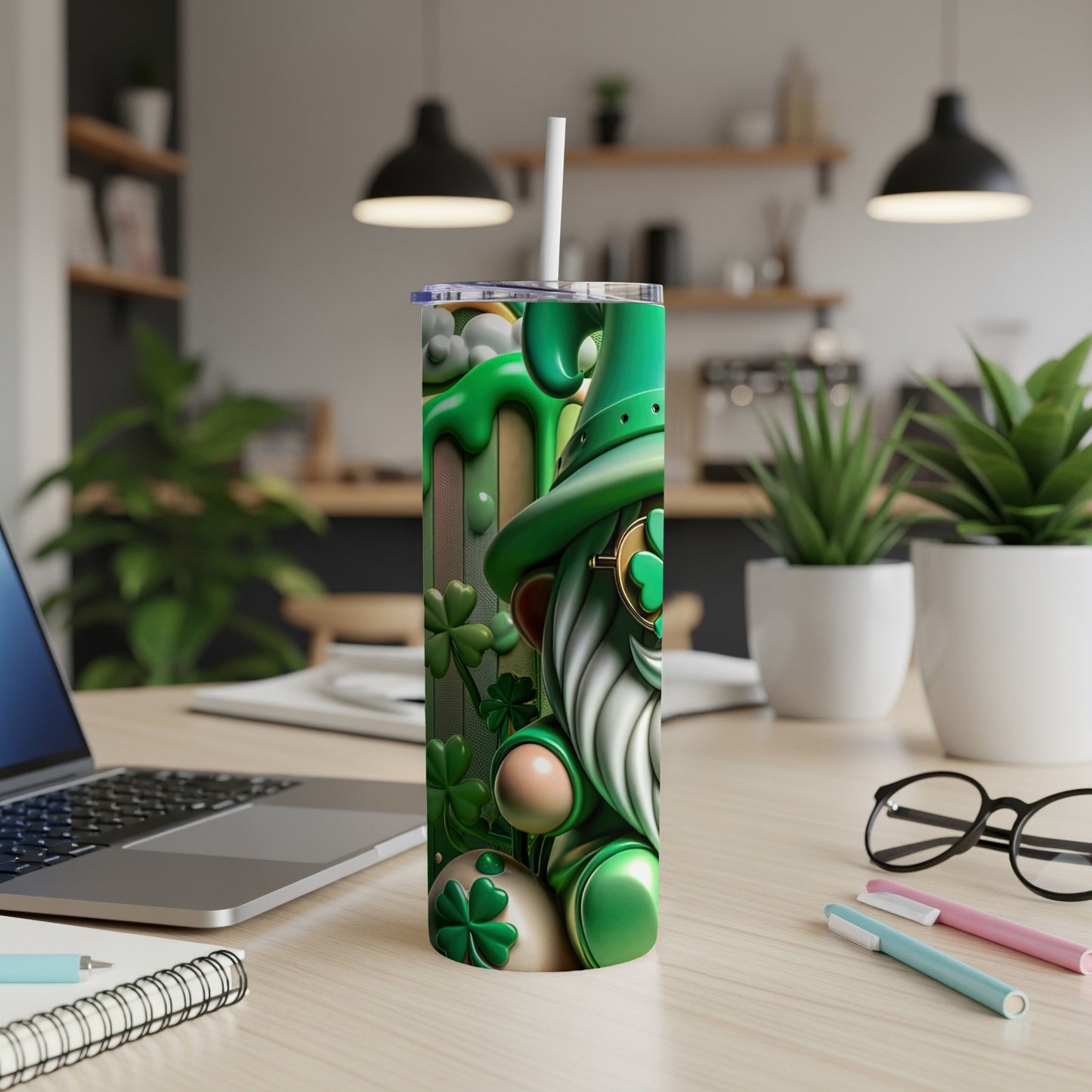 Green gnome with shamrocks on a tumbler next to a laptop.