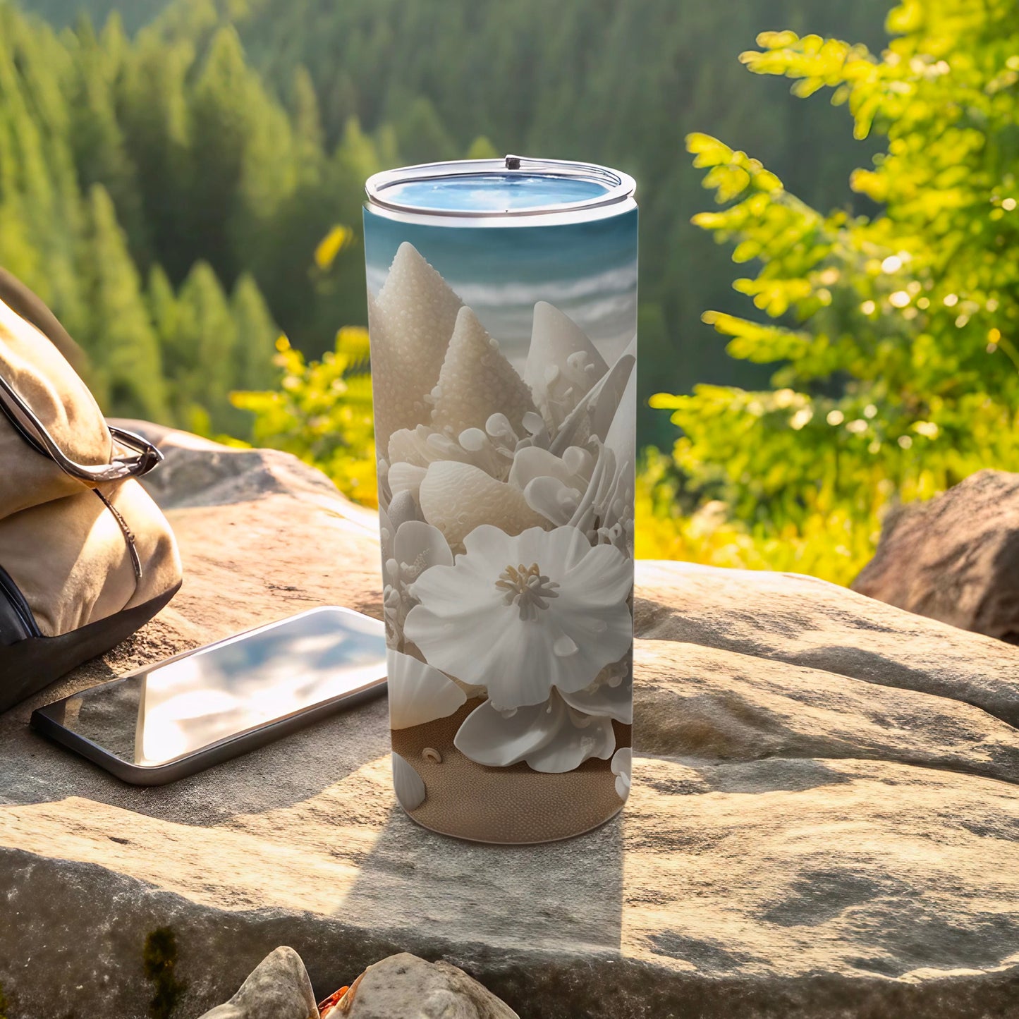 White floral design on a tumbler with a phone and backpack outdoors.