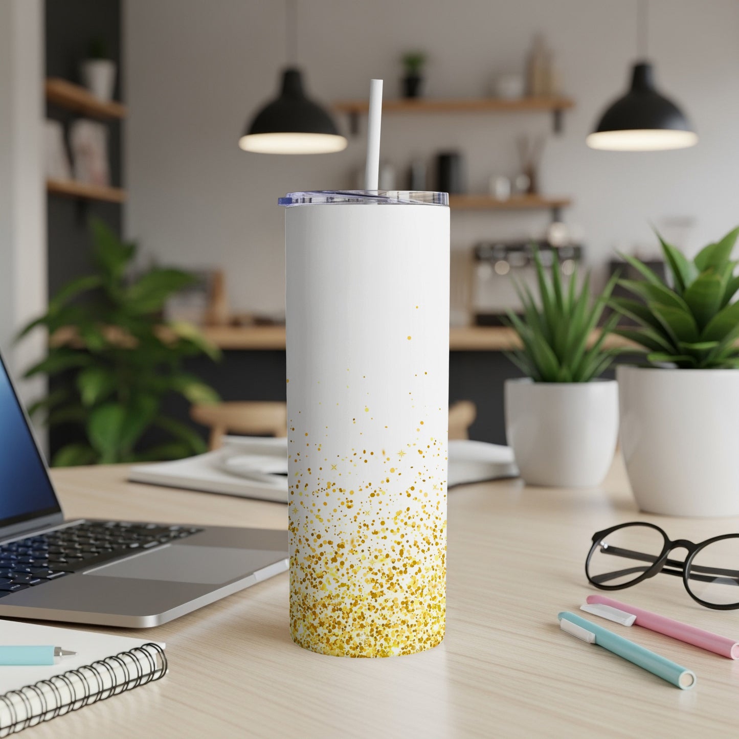 White tumbler with gold glitter design on a desk with laptop and pens.