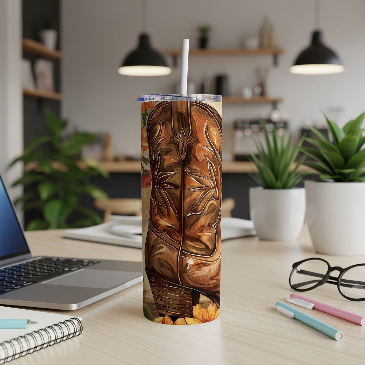 Brown cowboy boot tumbler with floral accents on a desk.