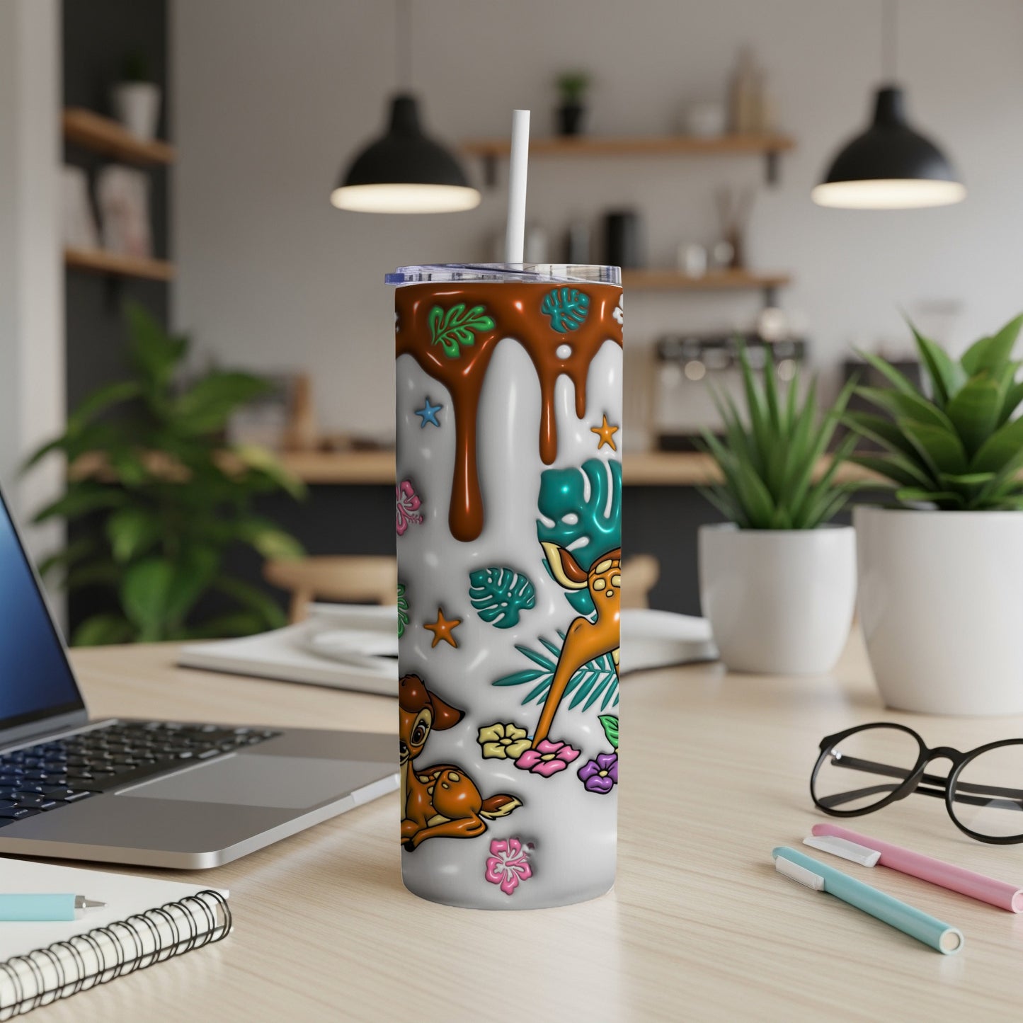 White tumbler with cartoon deer and tropical leaves, on a desk.