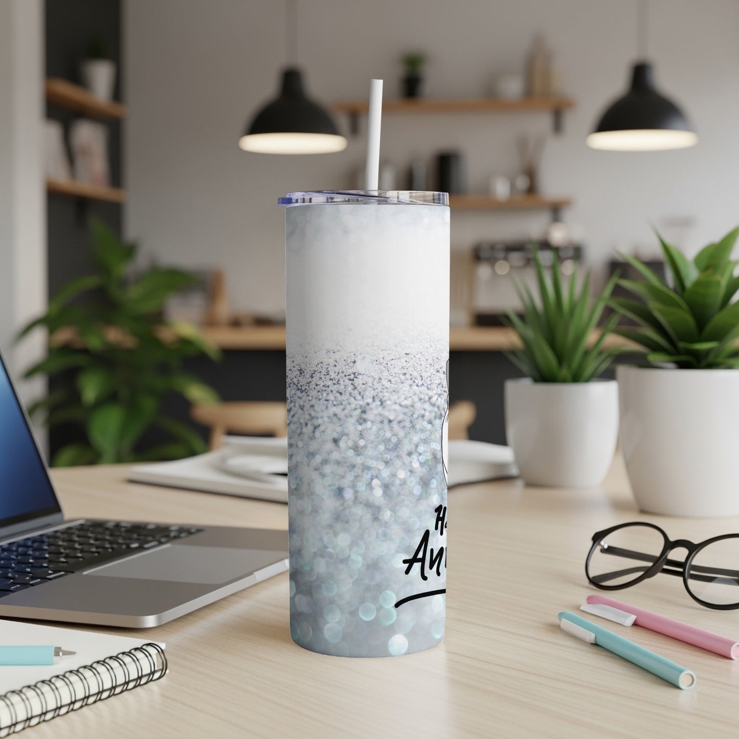 Silver glitter tumbler with "Happy Anniversary" text and straw on desk.
