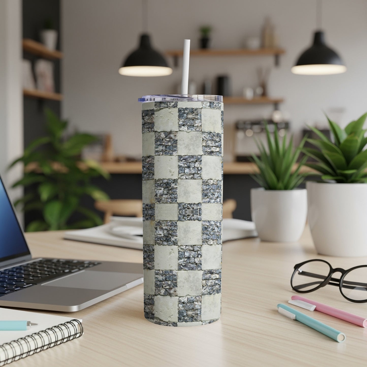 Checkerboard stone pattern tumbler with straw on a desk.