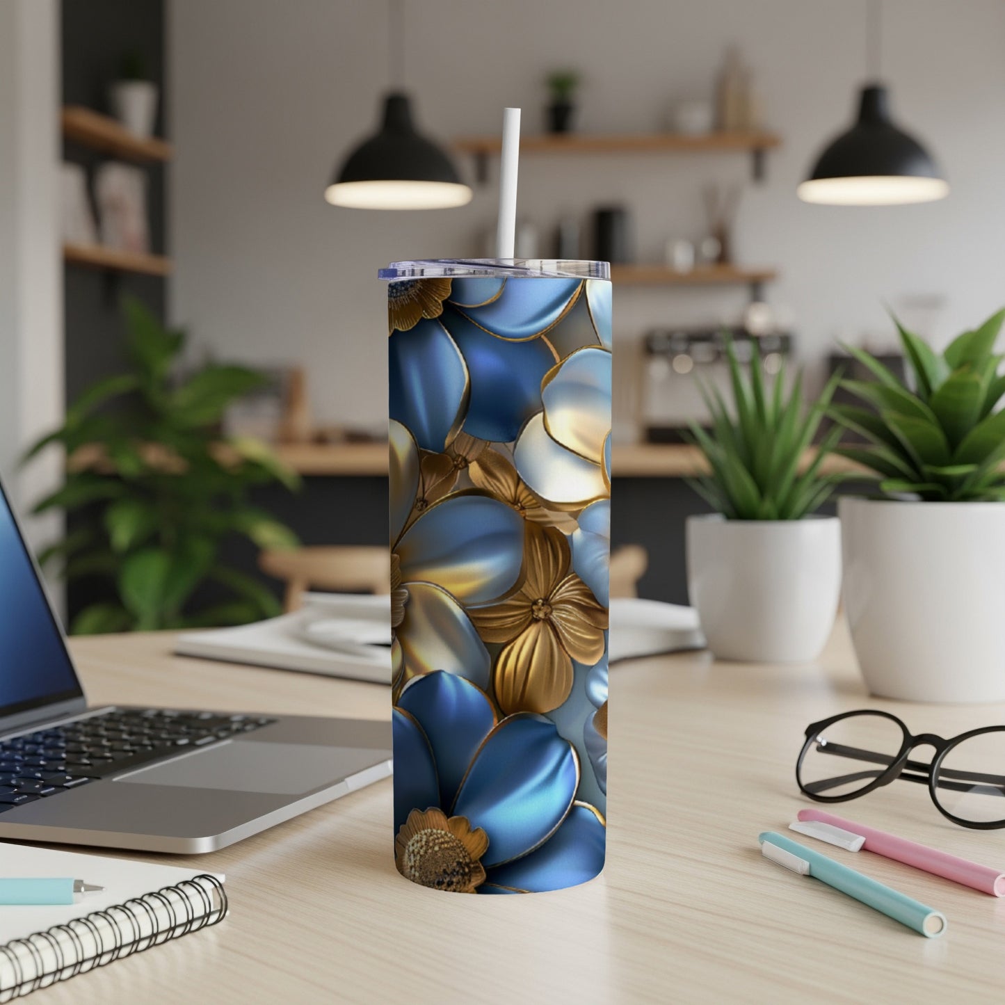 Blue and gold floral patterned tumbler on a desk with a laptop and pens.