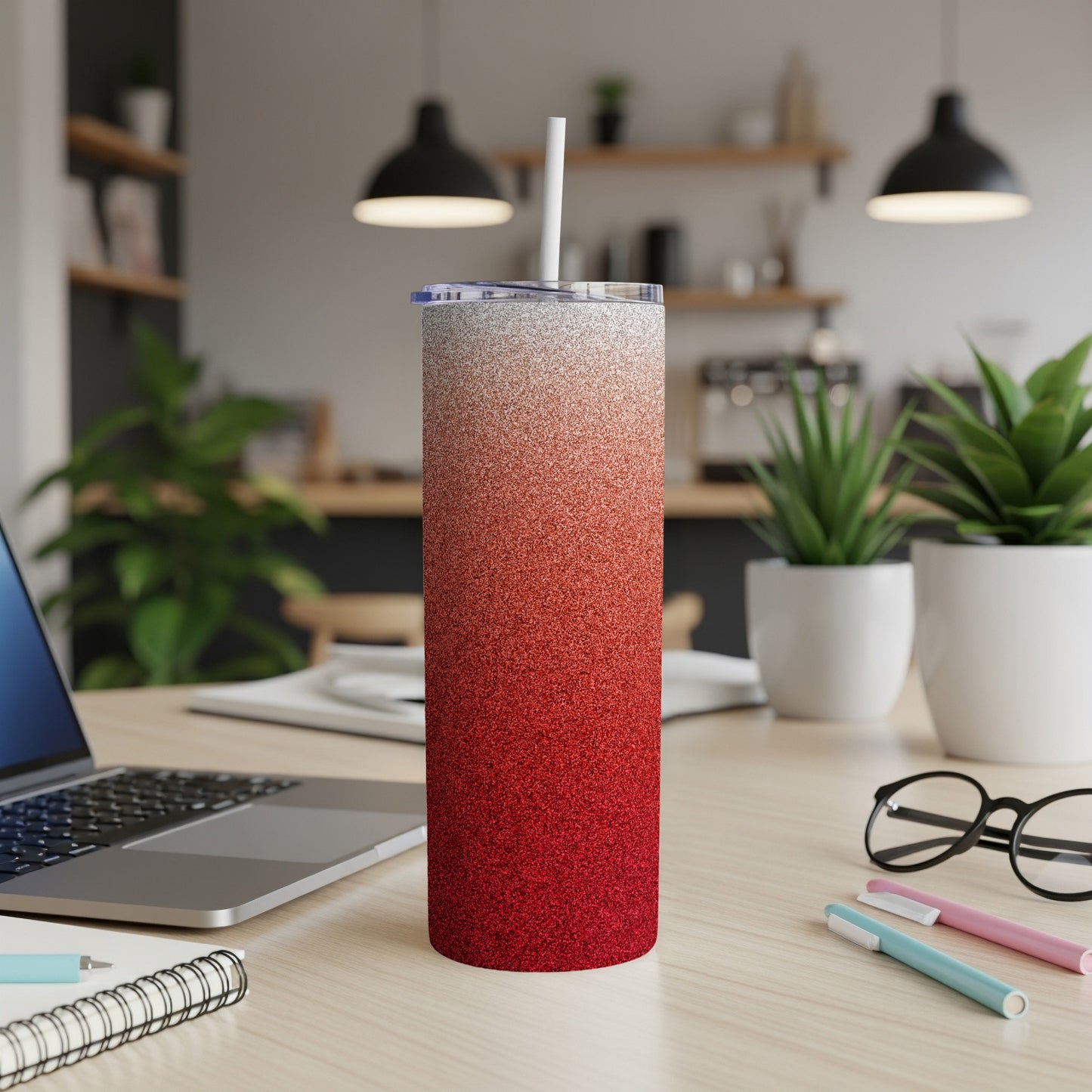Red and white glitter gradient skinny tumbler with straw on desk.