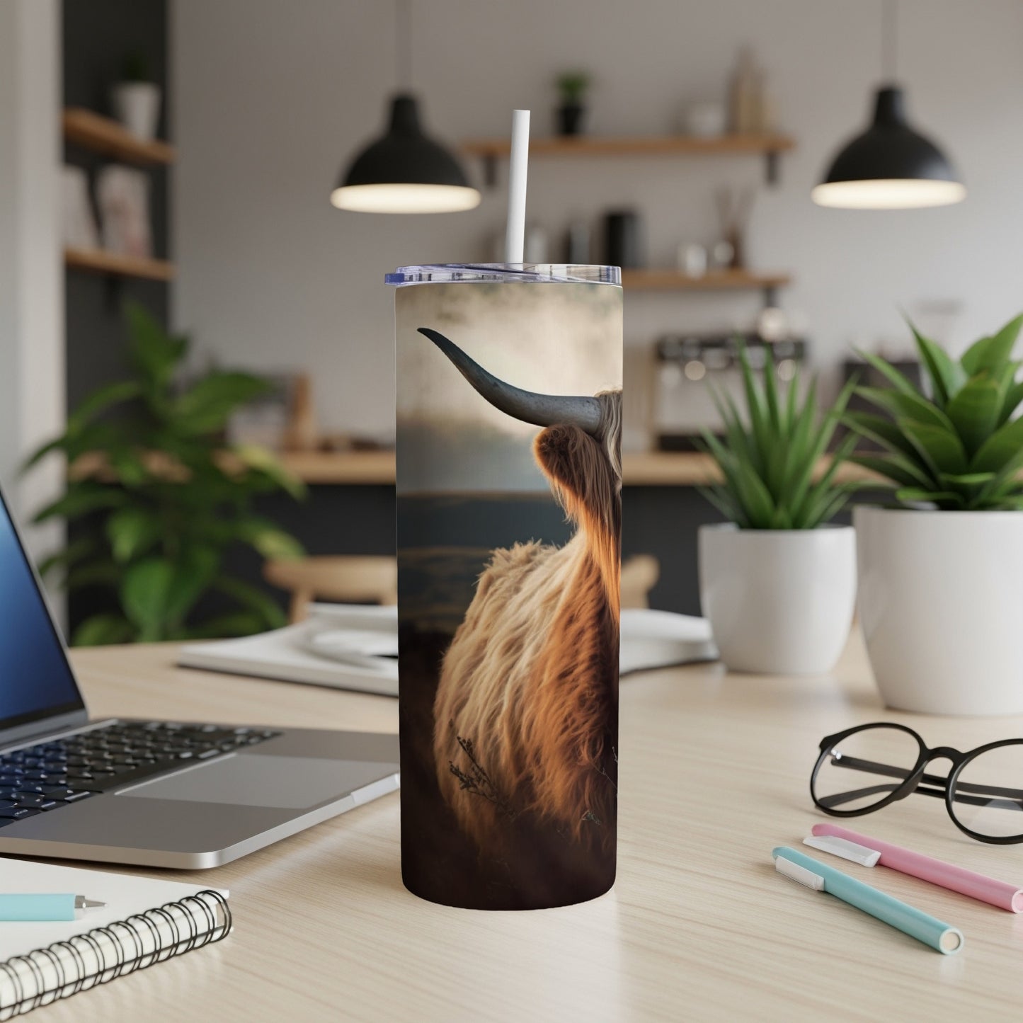 Highland cow on a tumbler with a straw, set on a desk.
